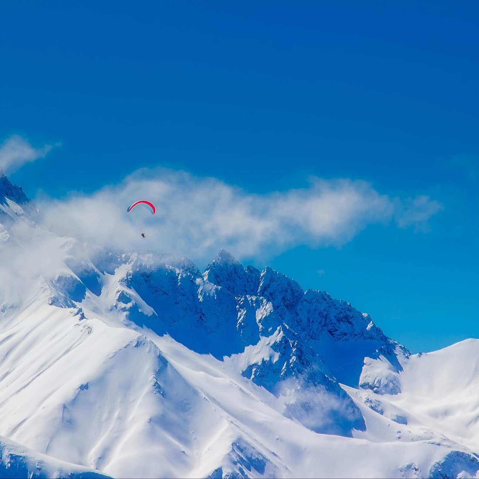 Une personne survole en parapente les montagnes des Alpes en France
