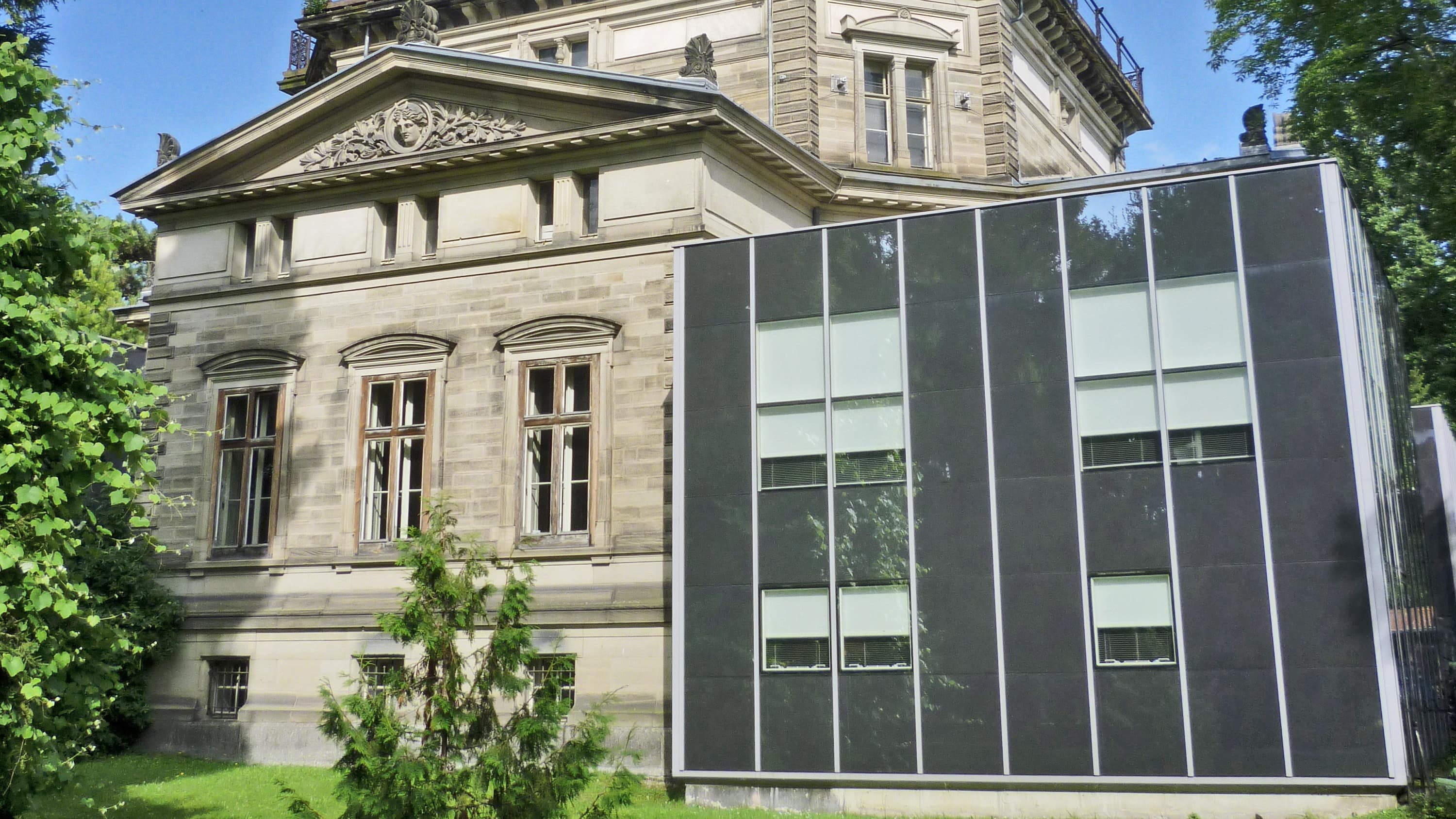 Vue sur le planétarium de Strasbourg, un arbuste et une pelouse en avant-plan