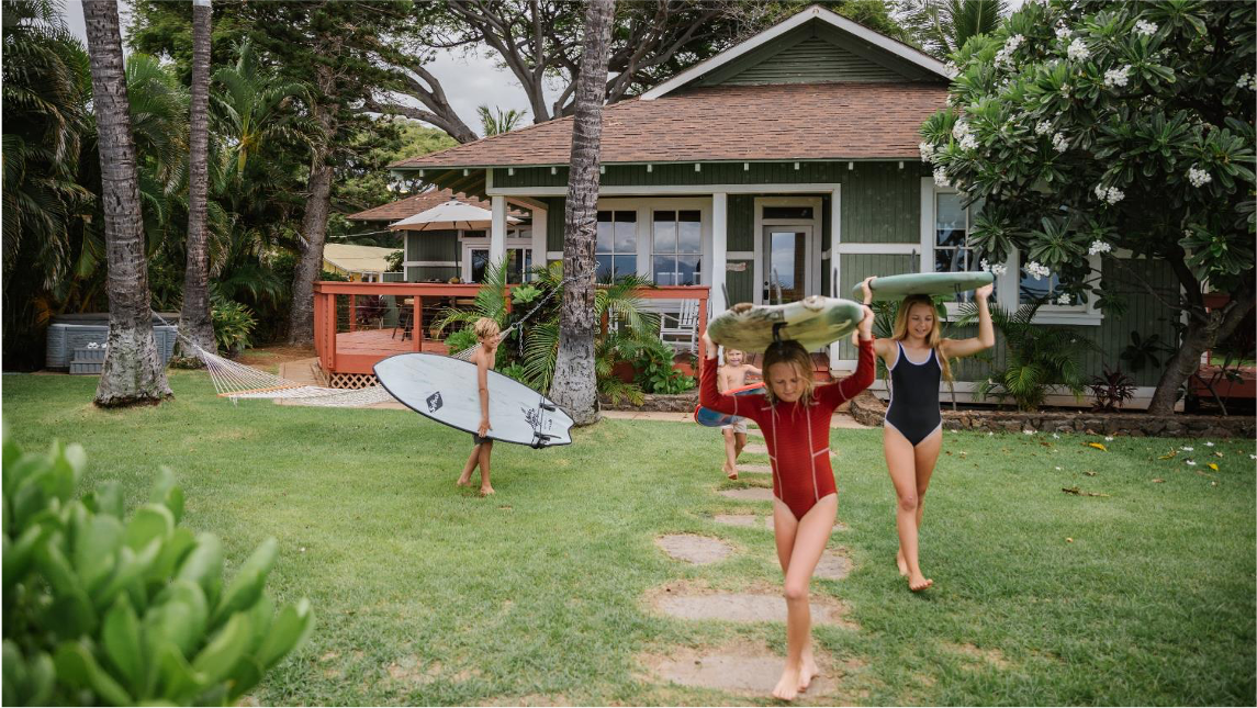 enfants tenant des planches de surf devant une location de vacances