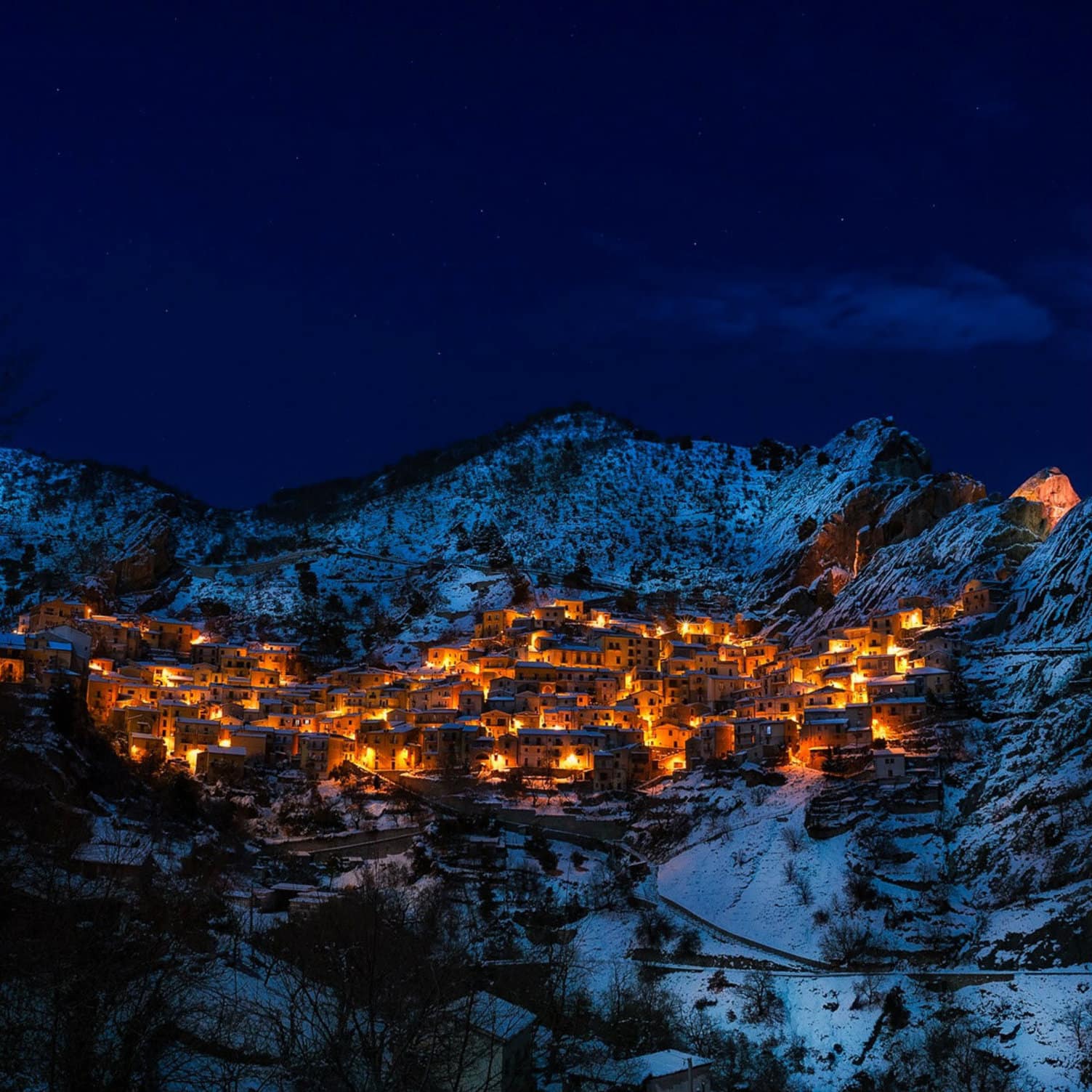 Un village de montagne éclairé au milieu des montagnes en hiver