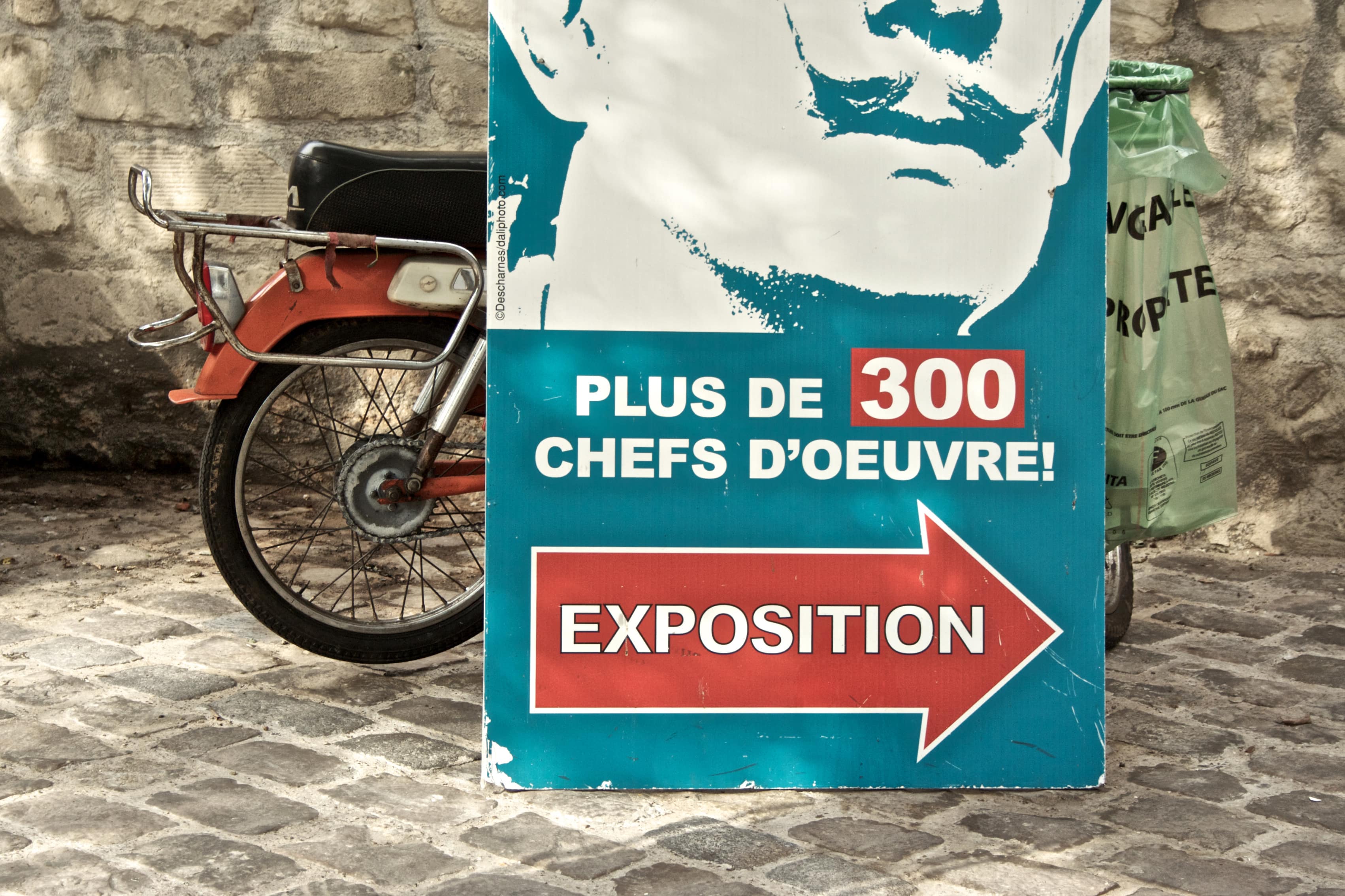 Affiche d’exposition sur laquelle on reconnaît le bas d’un portrait de Salvador Dali