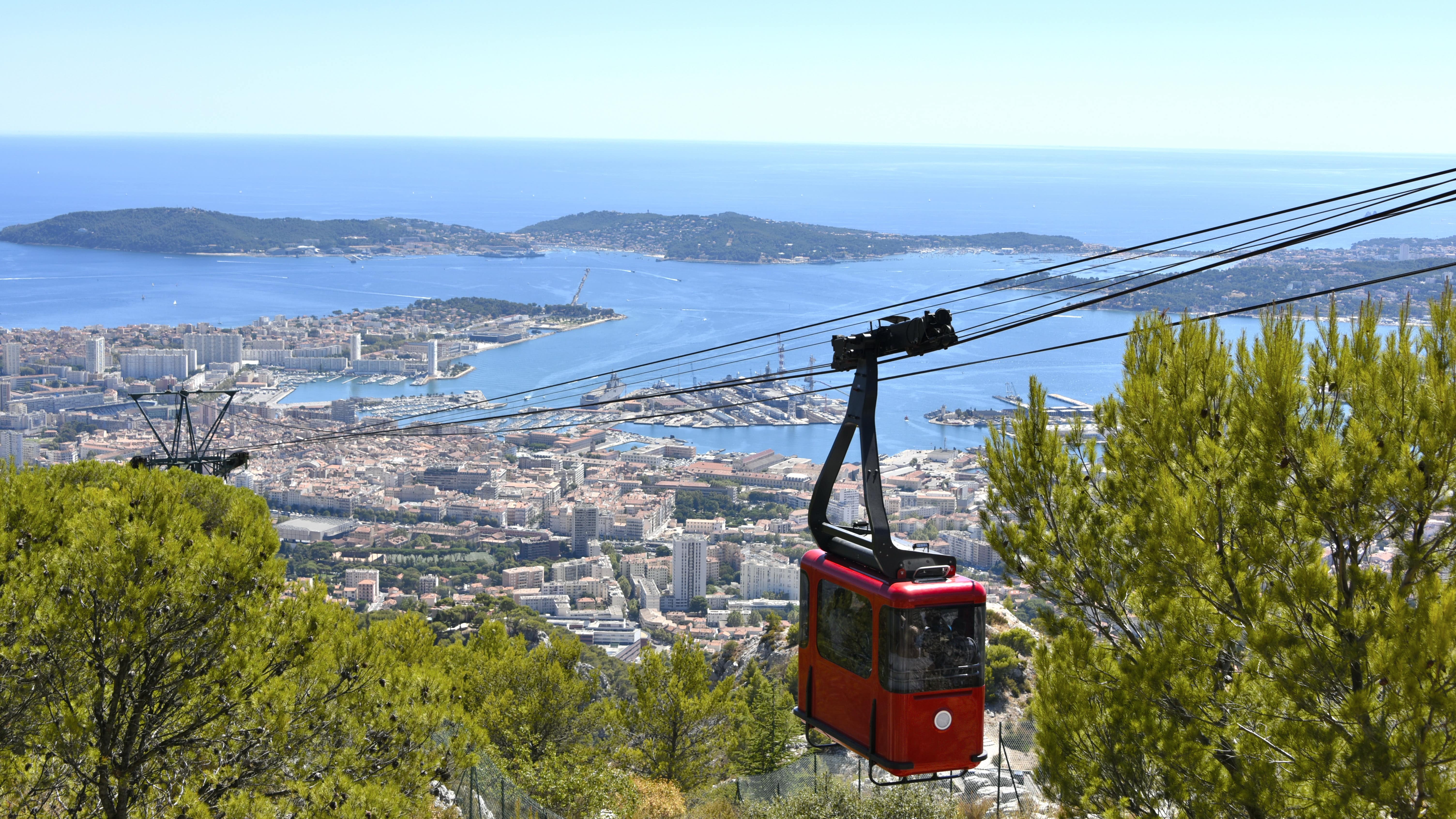 Vue sur Toulon et sa baie depuis le mont Faron, avec une cabine rouge de téléphérique au premier plan