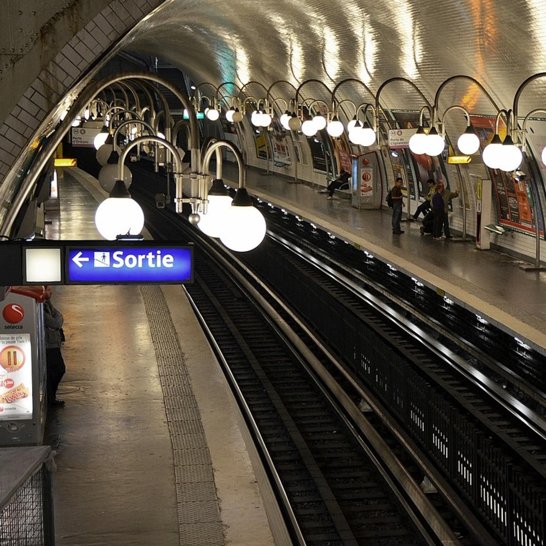 Vue intérieure d'une station de métro parisien. Rails, quais et lampadaires de la RATP
