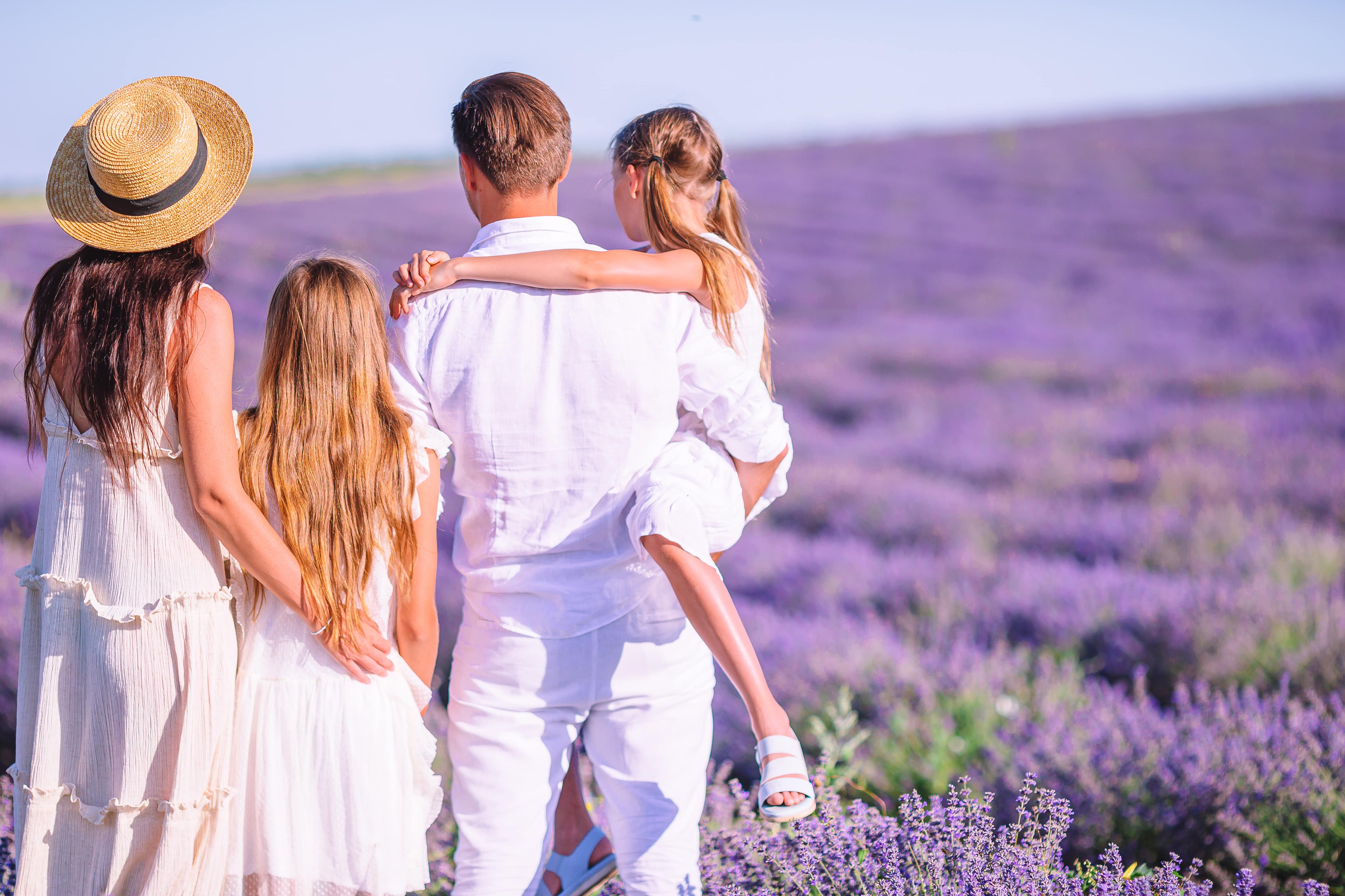 Famille dans le champ de fleurs de lavande au coucher du soleil en robe blanche et chapeau