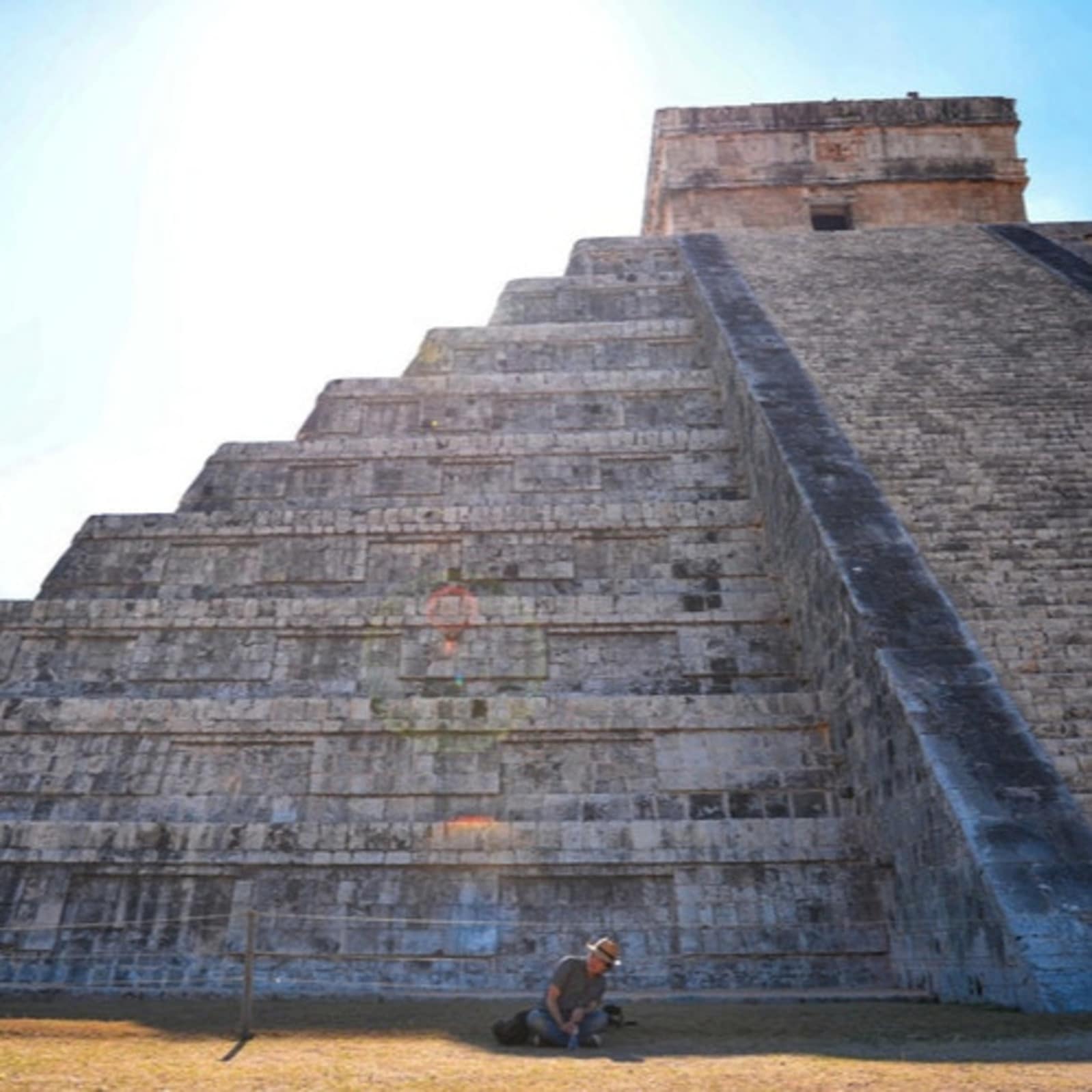 Homme assis par terre devant une pyramide