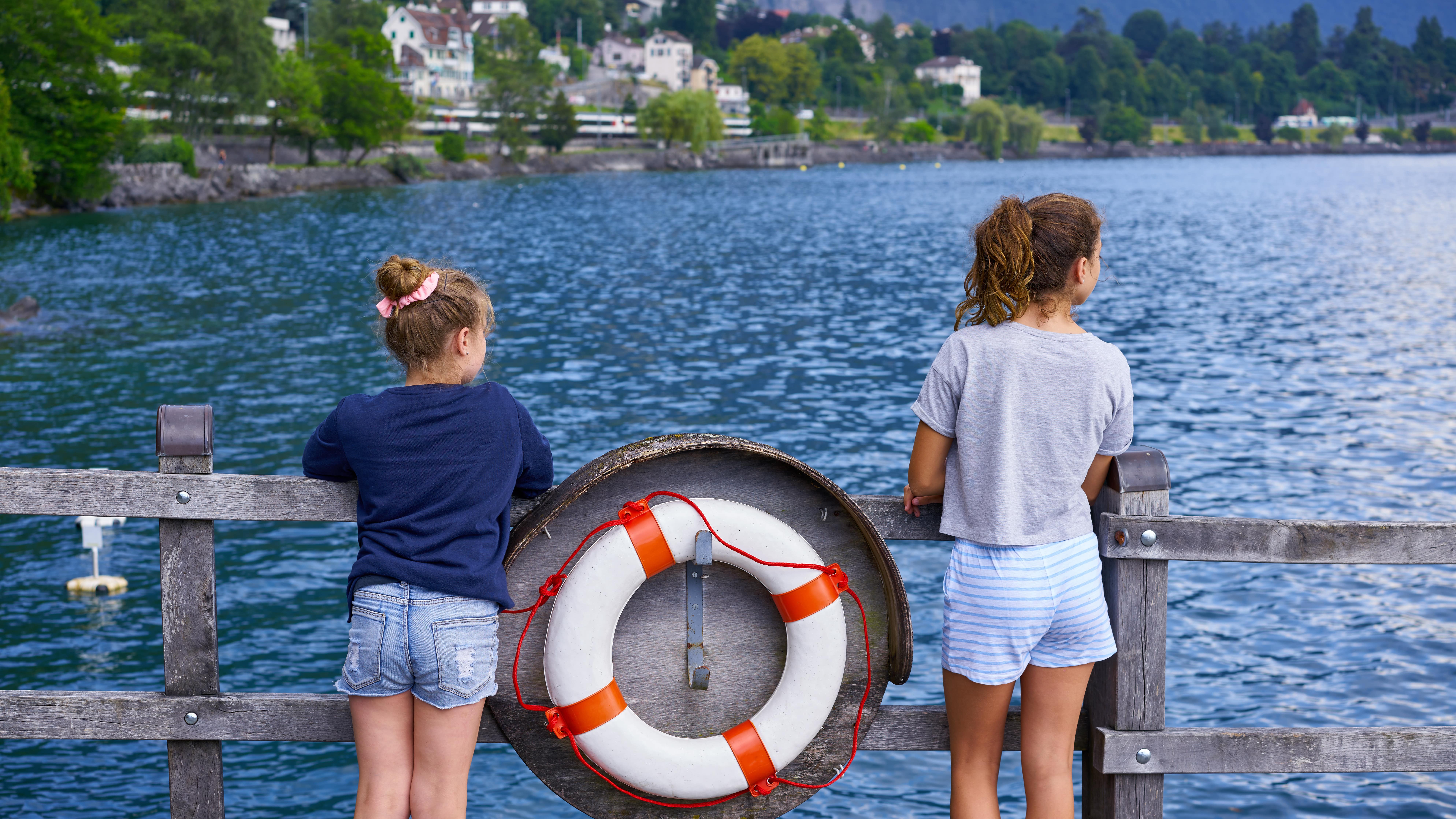 Deux jeunes filles accoudées à une barrière en bois sur le lac Léman