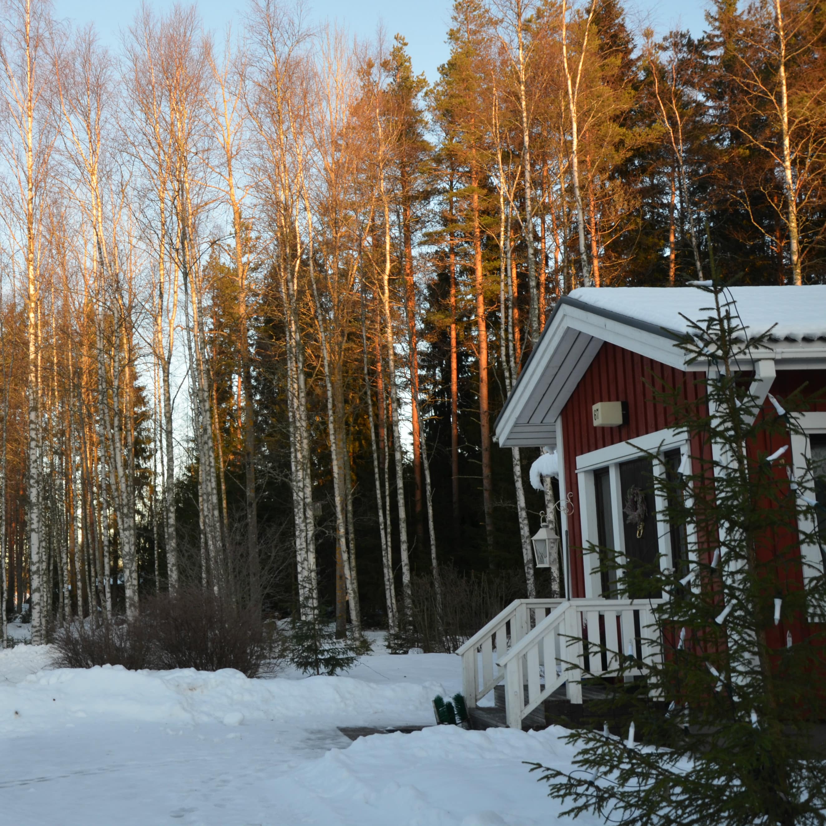 Chalet en bois rouge dans un décor montagnard et enneigé au coucher du soleil