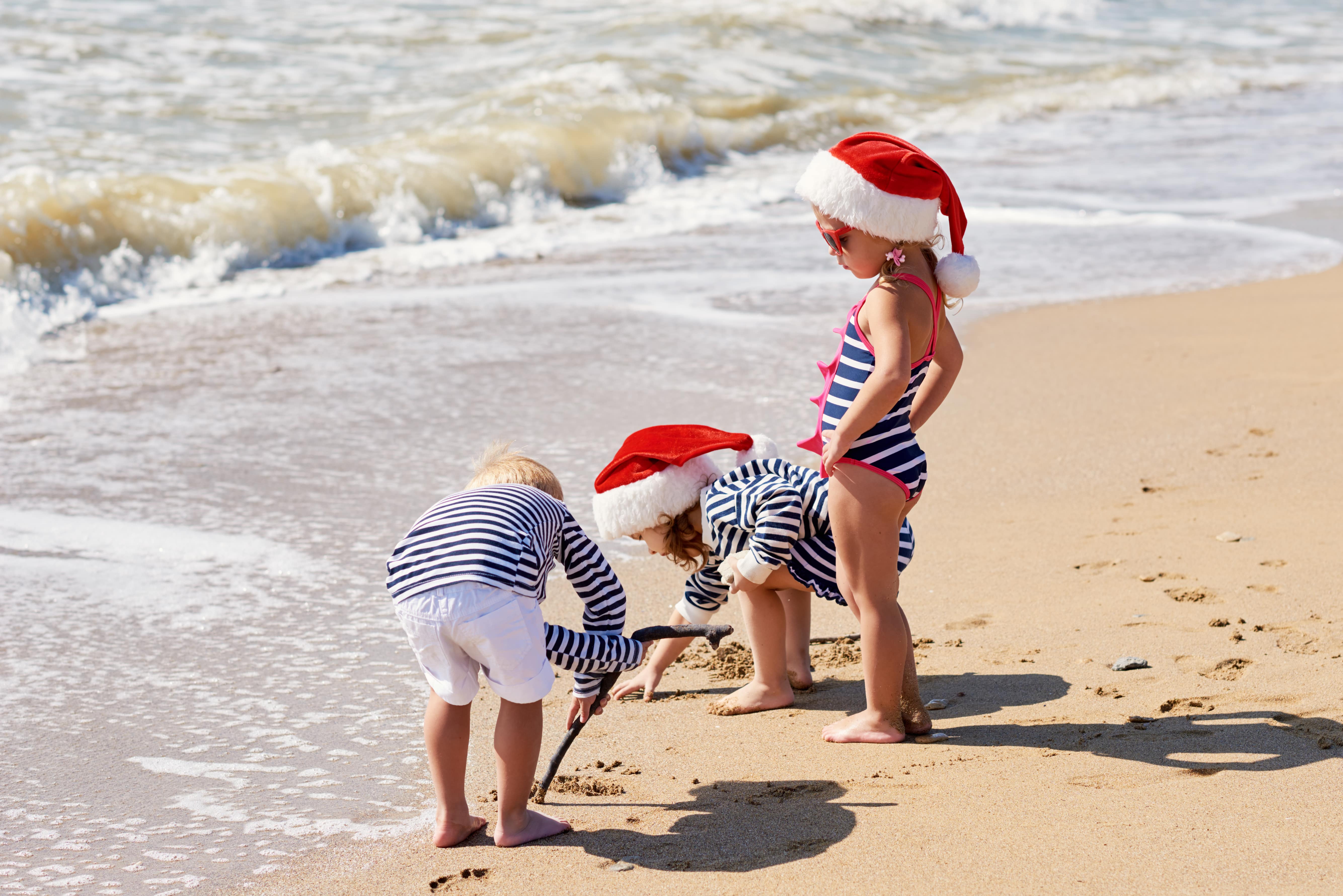 enfants jouant dans des chapeaux de père noël sur le sable enfants jouant dans des chapeaux de père noël sur le sable children playing in santa claus hats sur la plage