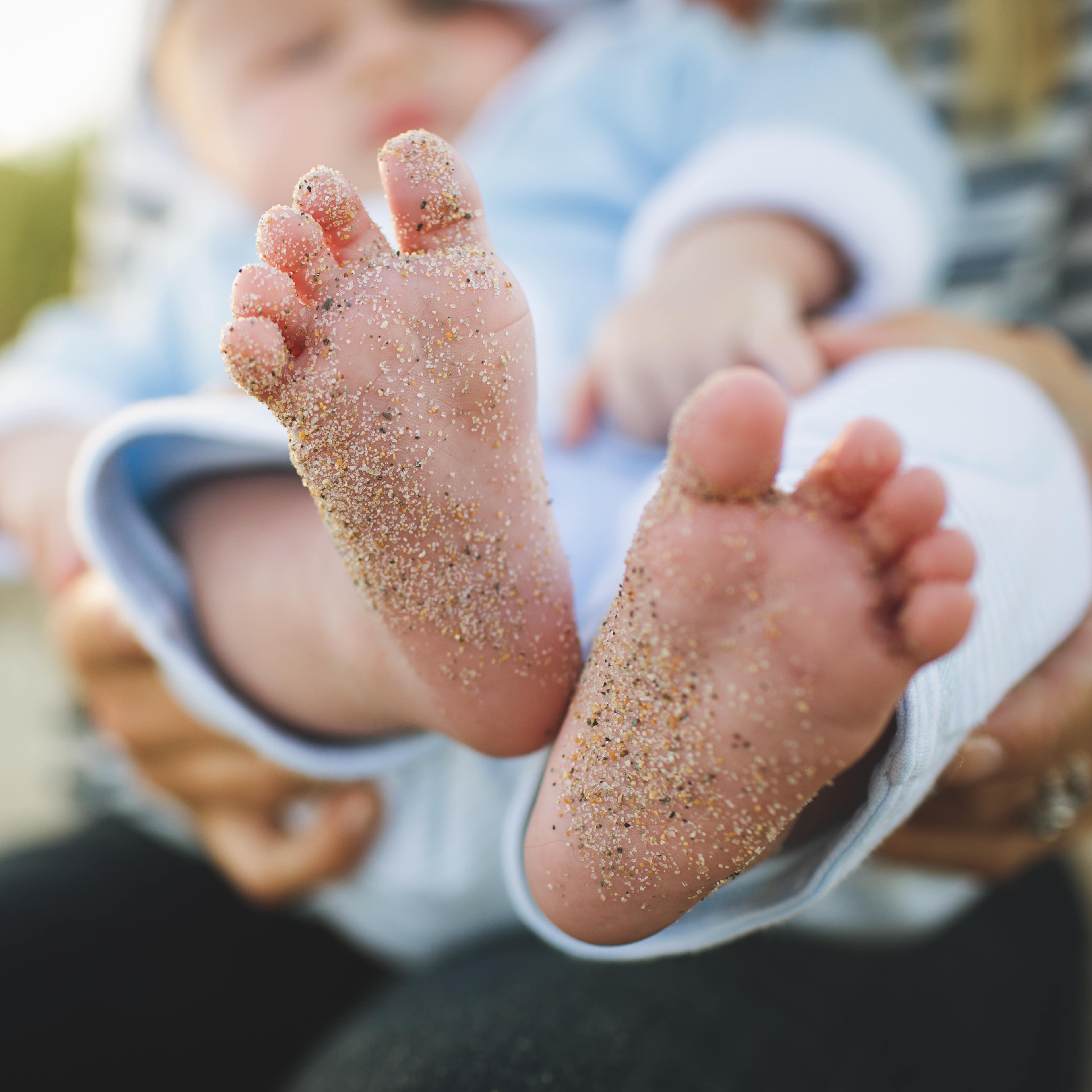 Pieds de bébé avec du sable, vacances avec bébé