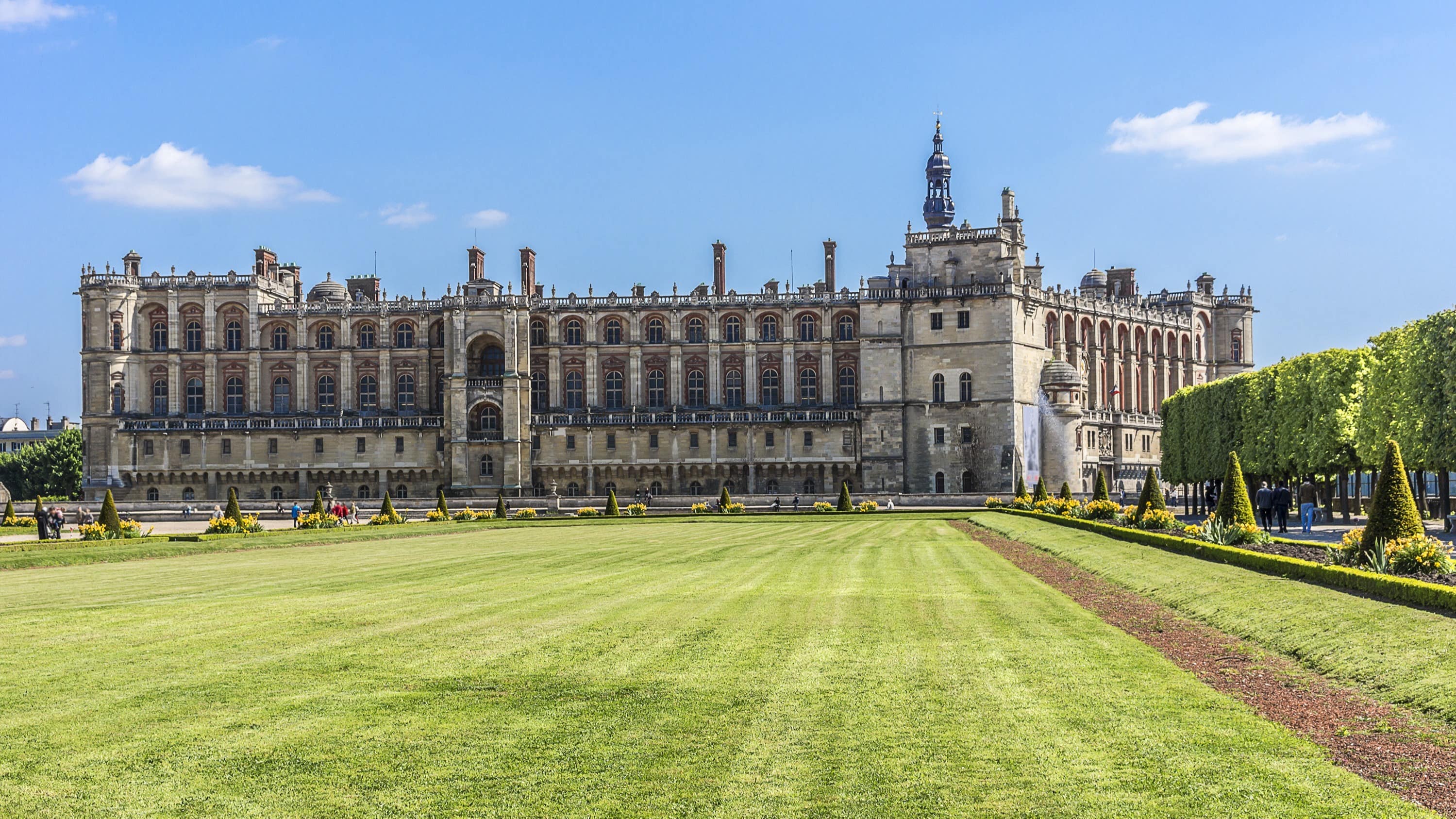 Une grande pelouse entourée de parterres de fleurs et le château de Saint-Germain-en-Laye