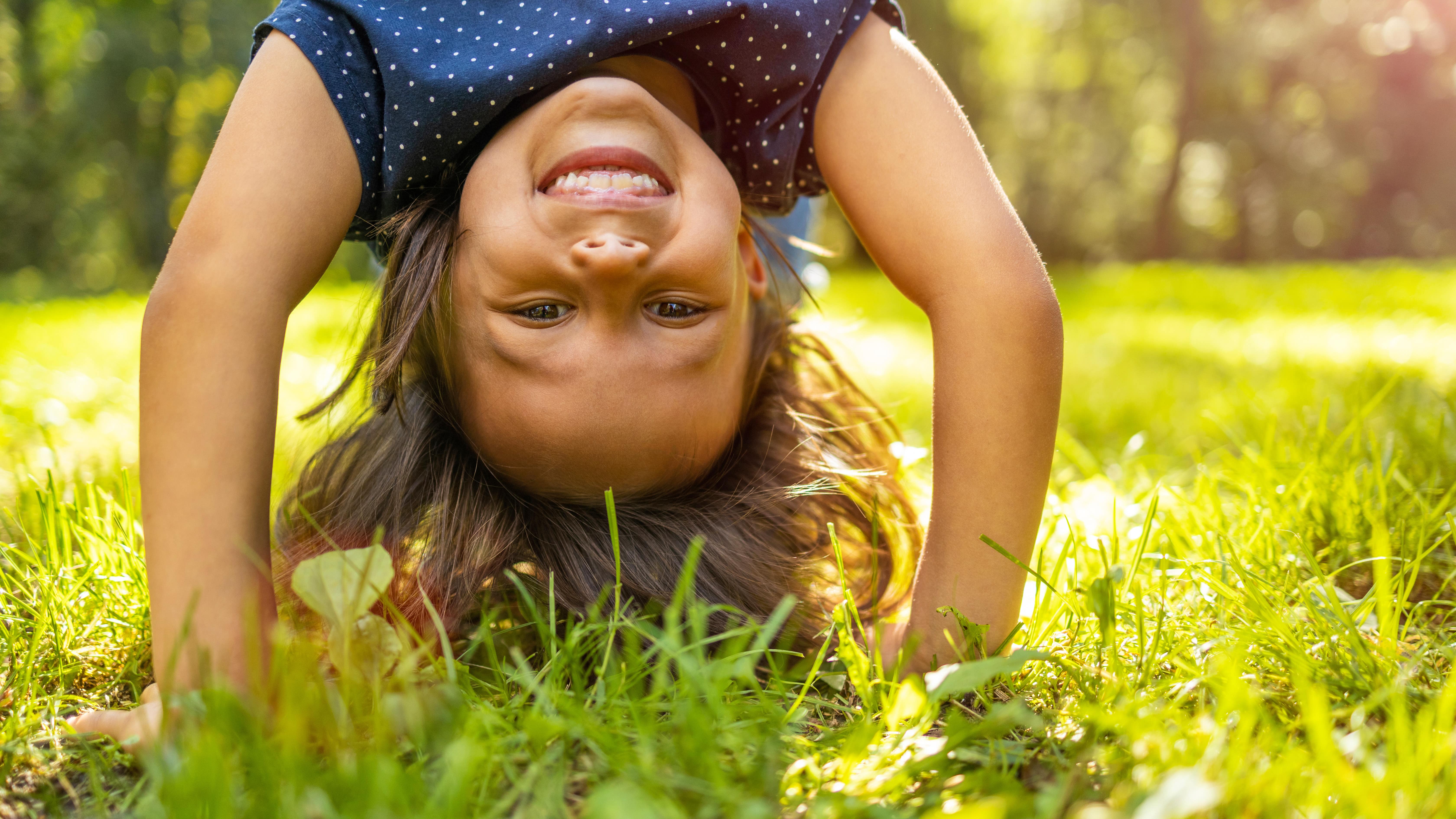 Enfant qui fait le poirier dans l’herbe