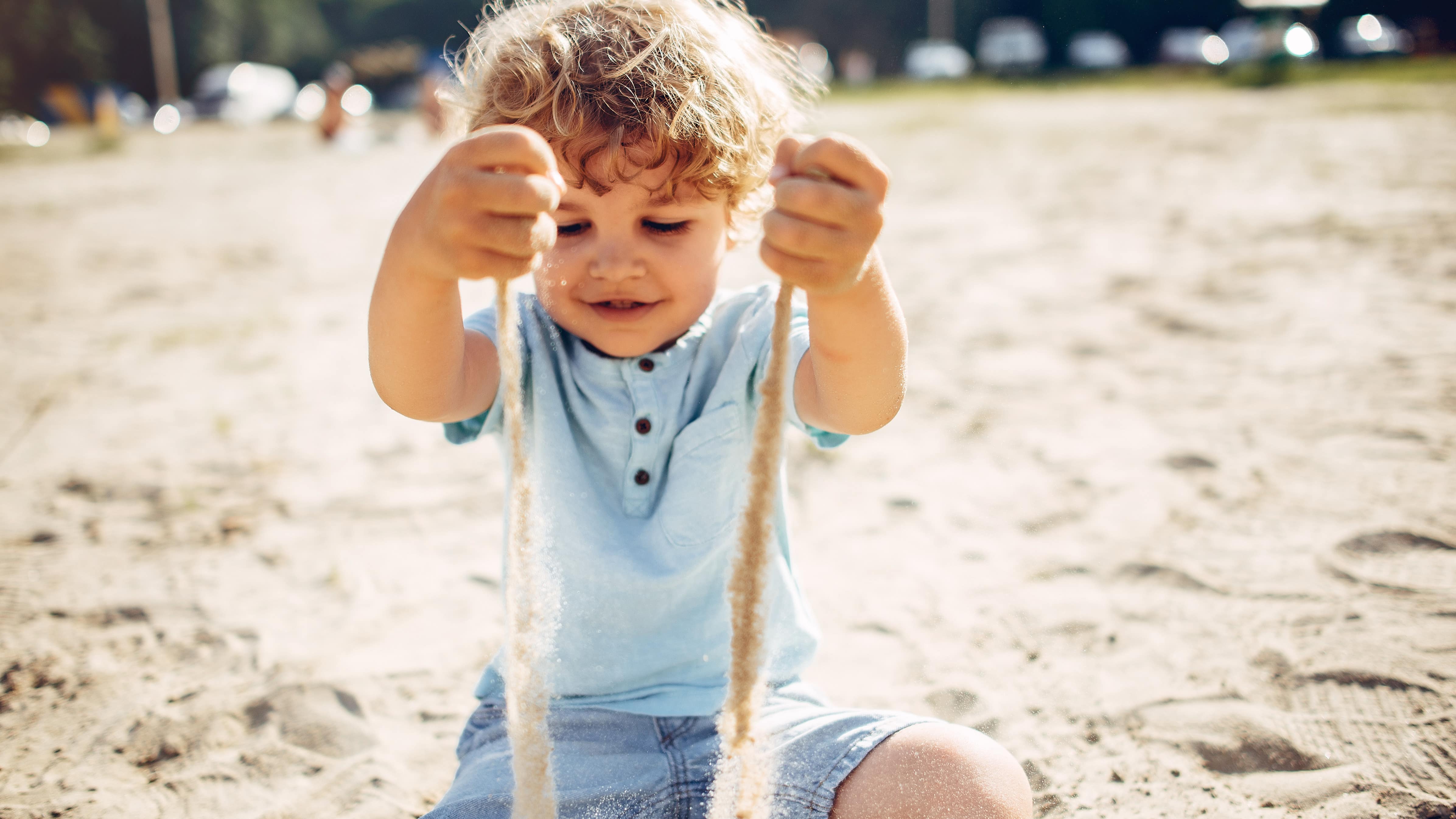 Un enfant assis laisse couler du sable entre ses mains