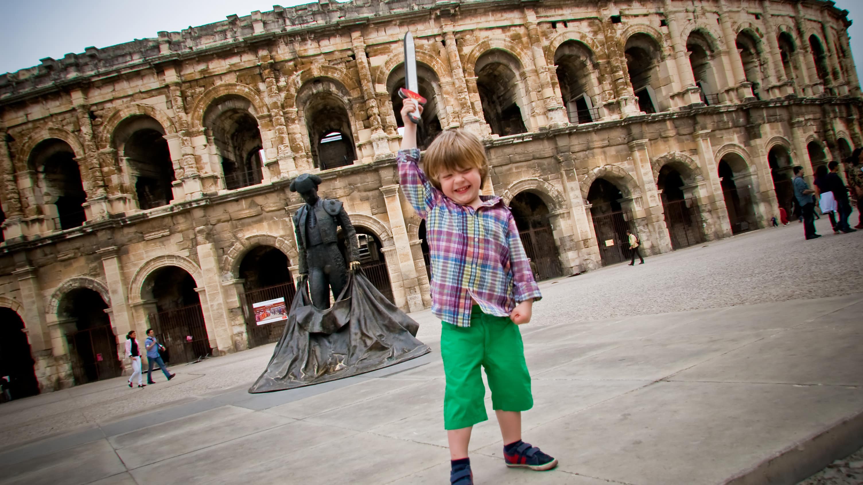 Garçonnet jouant avec une fausse épée devant les arènes de Nîmes