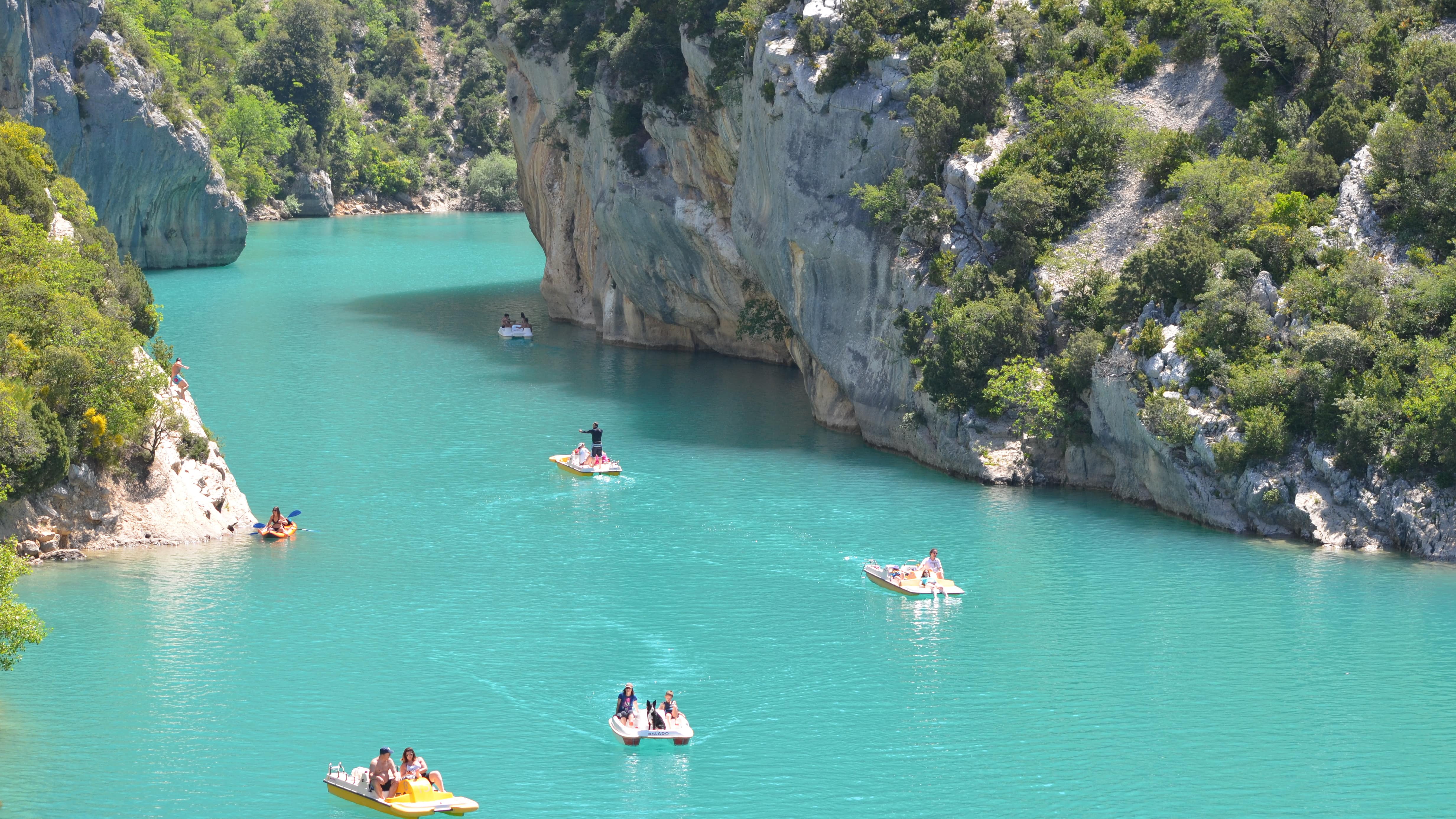 Des familles sur des pédalos et un kayak à la sortie des gorges du Verdon sur le lac de Sainte-Croix
