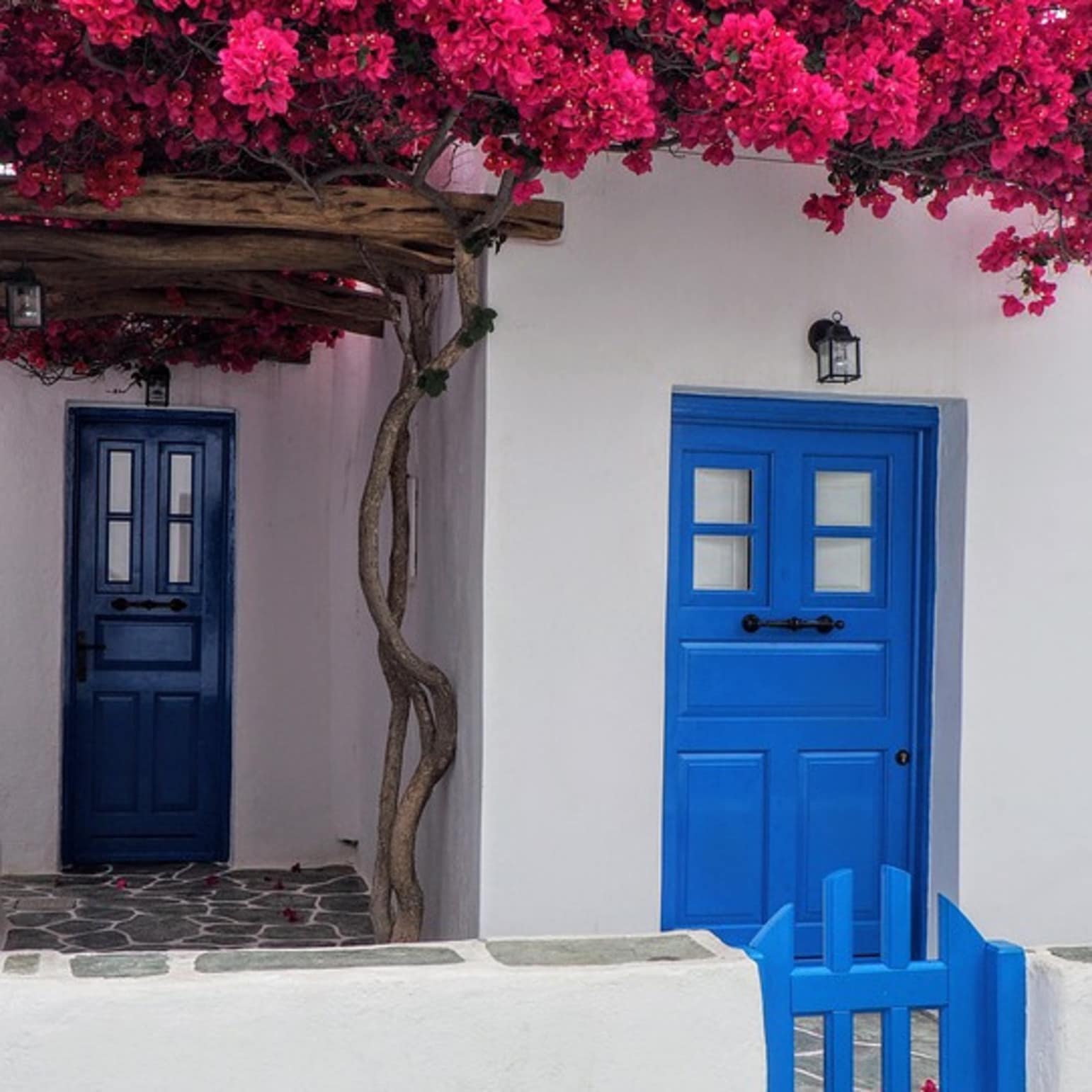 Façade de maison grecque, porte bleue, fleurs rose, villa Grèce