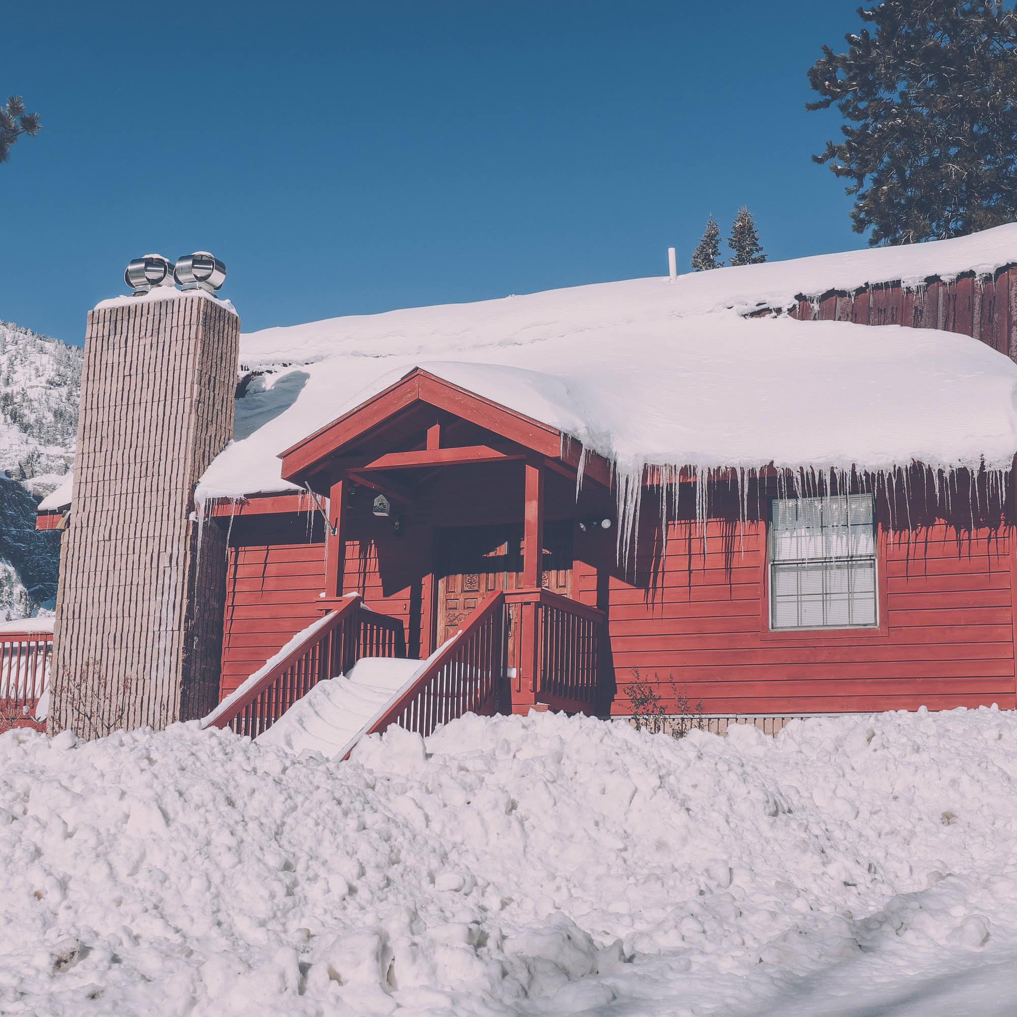 Une maison rouge en bois recouverte de neige dans un paysage de montagne