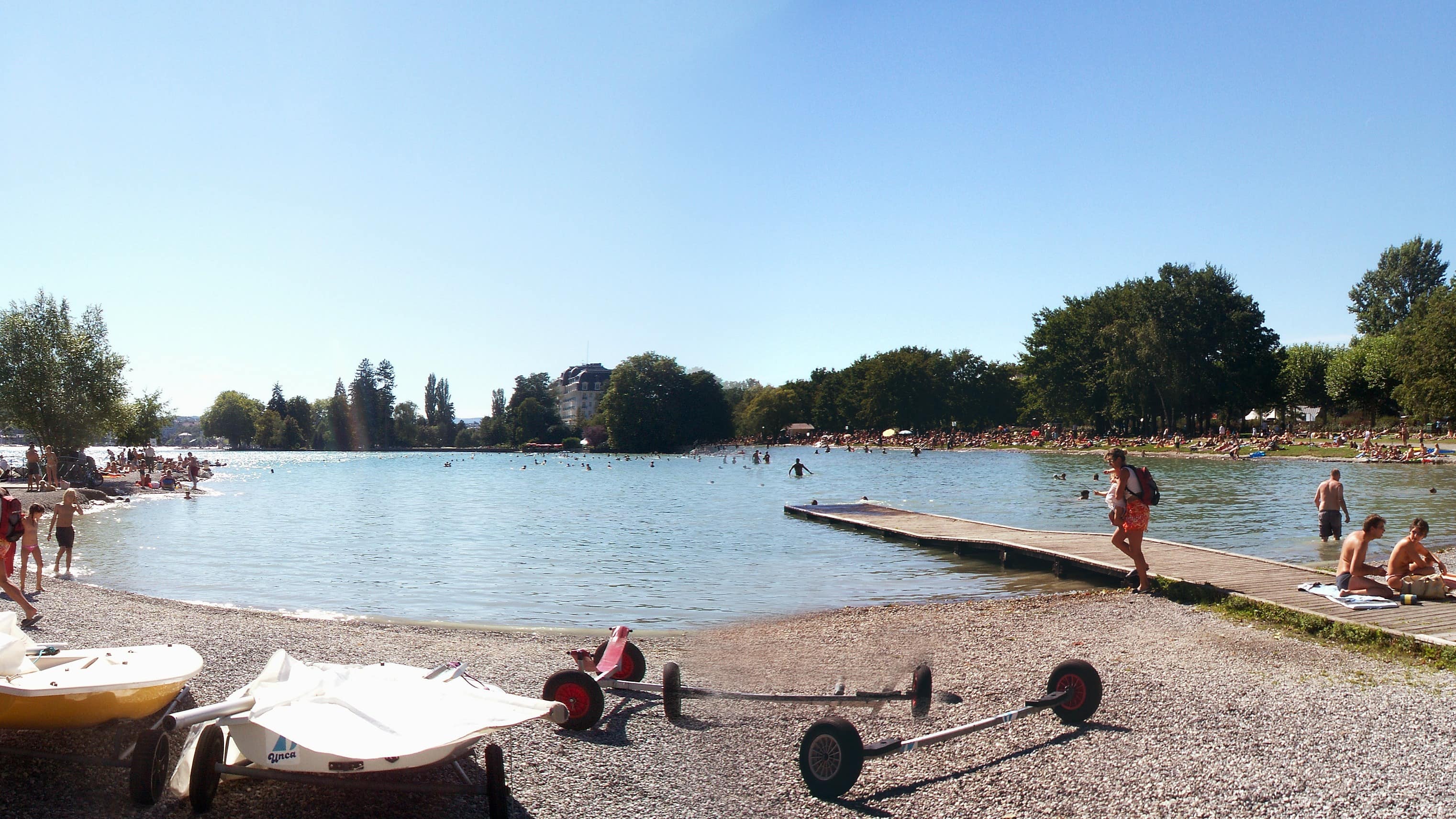 Des personnes en maillot de bain ou se baignant sur une plage du lac d’Annecy