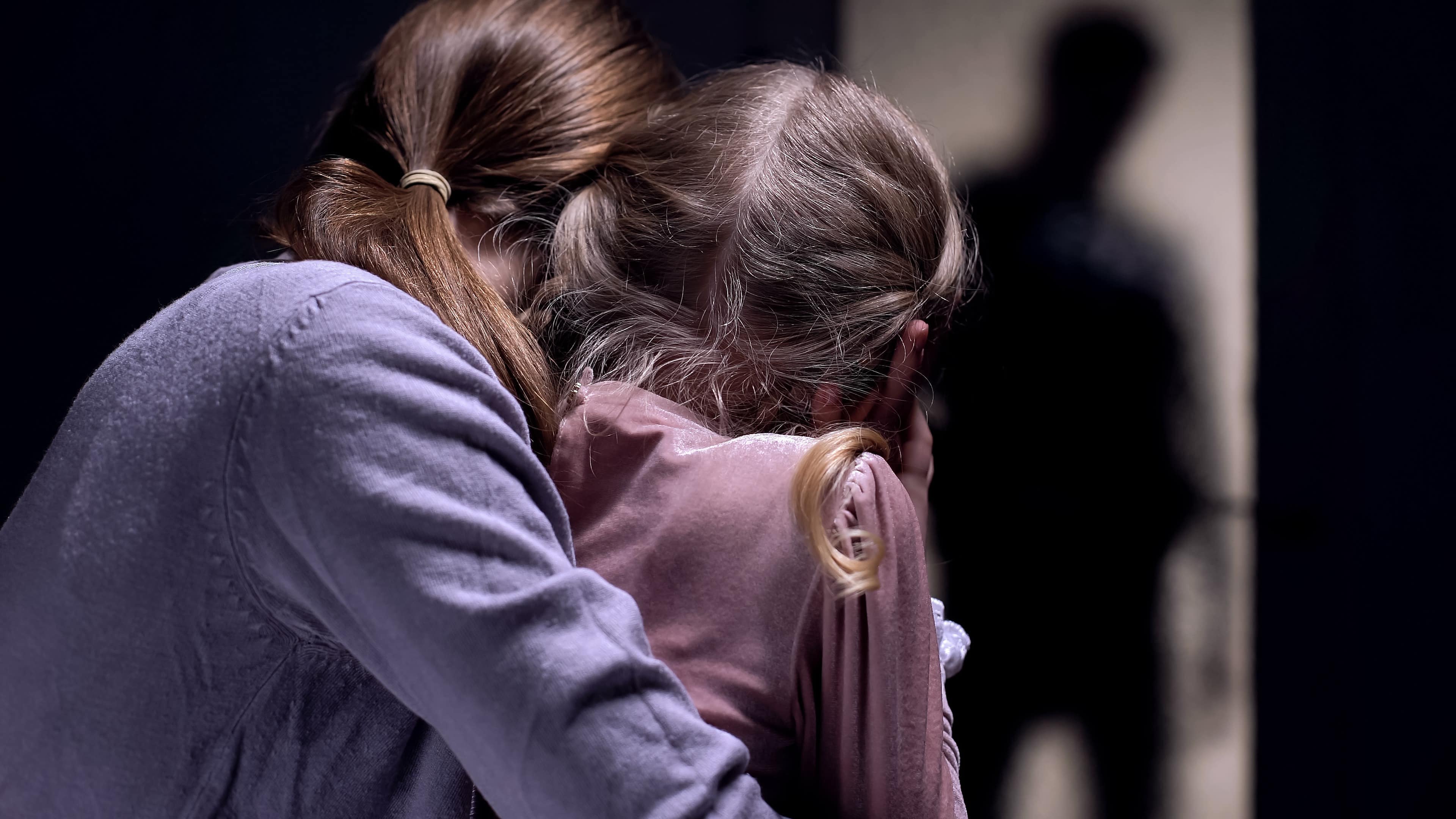 Une mère et sa fille de dos, face à une silhouette