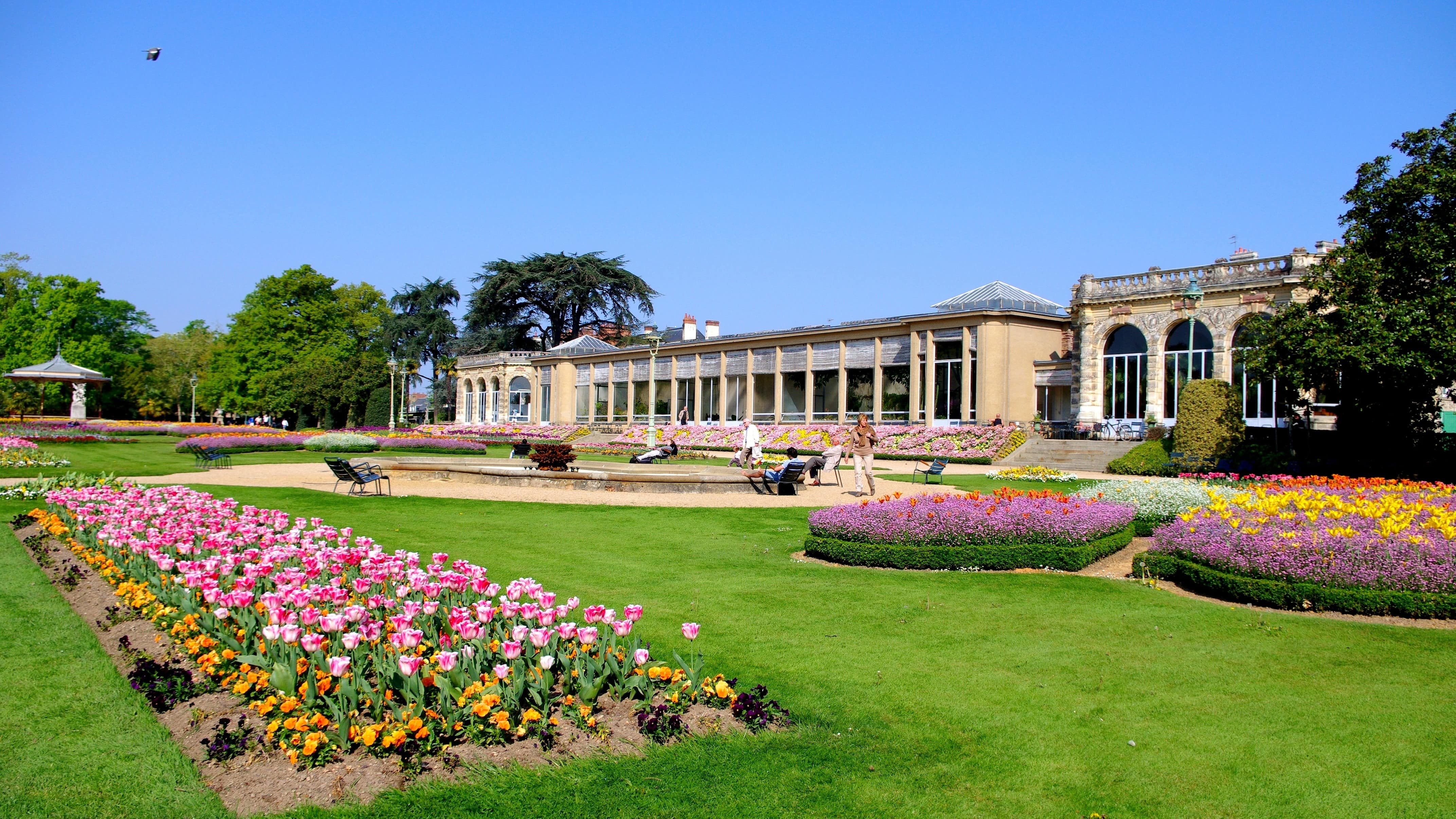 Vue sur le parc du Thabor, notamment des parterres de fleurs, et un bâtiment en arrière-plan