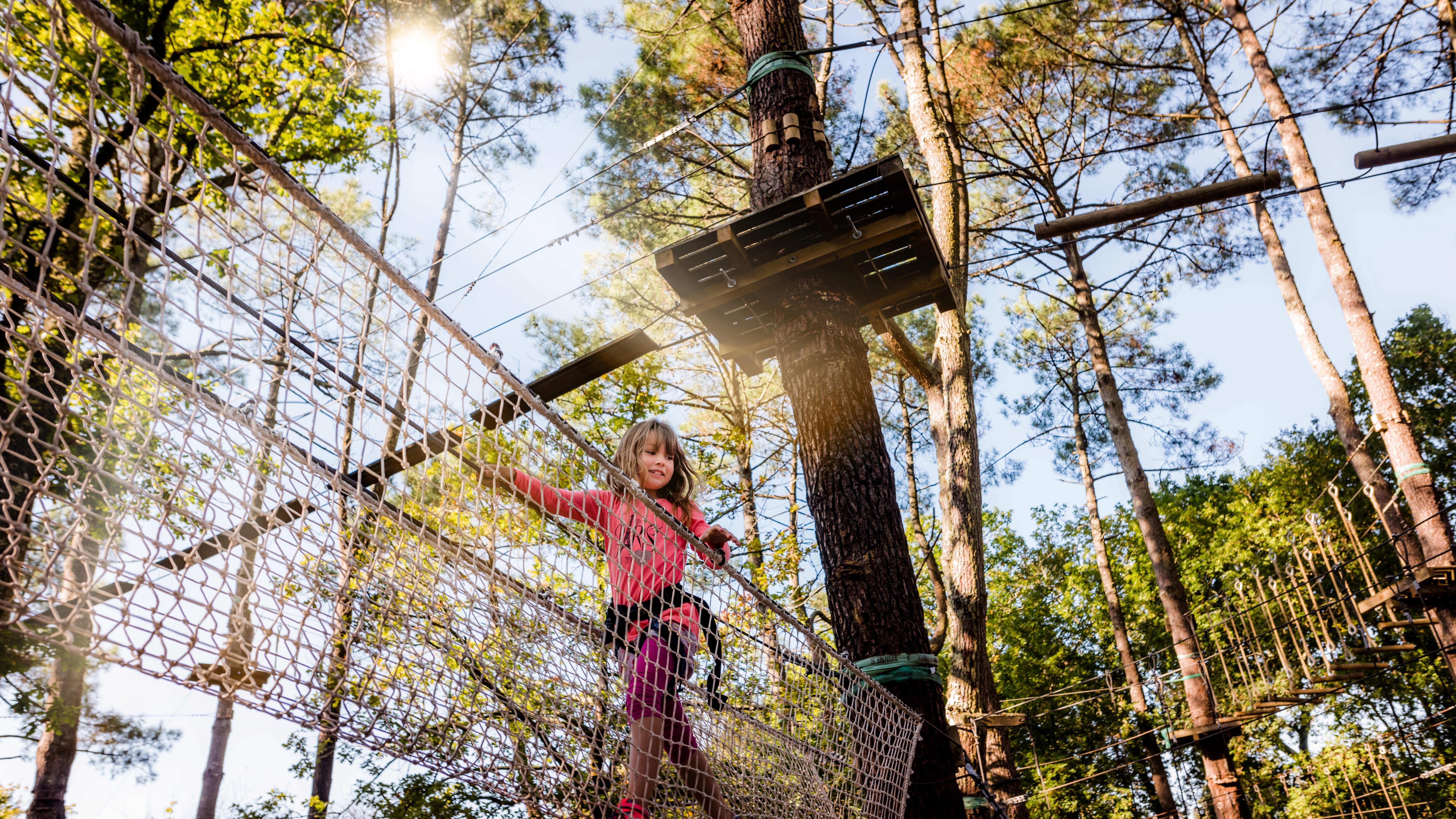 Vue d'en bas vers une petite fille faisant de l'accrobranche