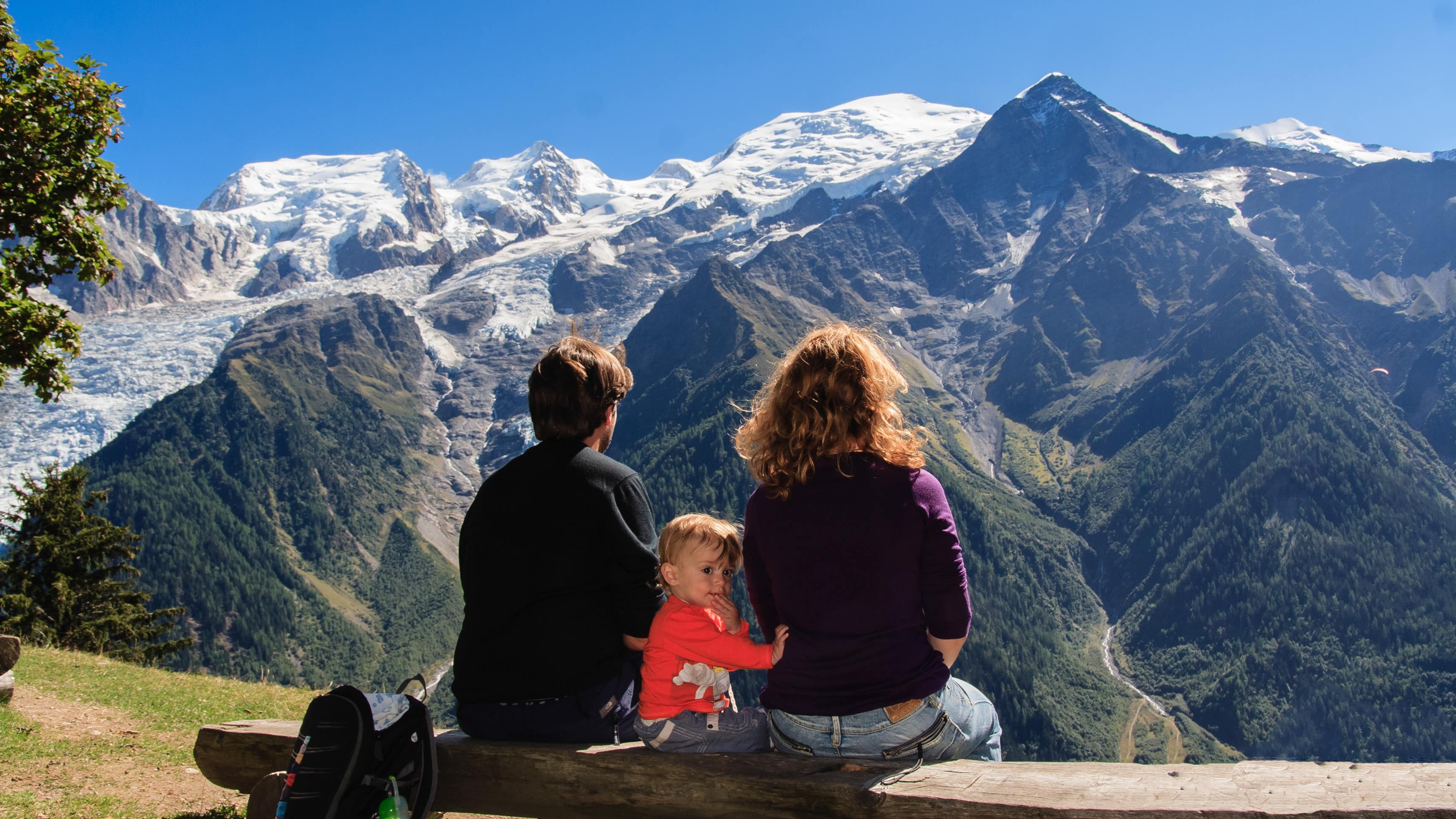 Petit garçon assis sur un banc entre ses parents admirant la vue sur le mont Blanc