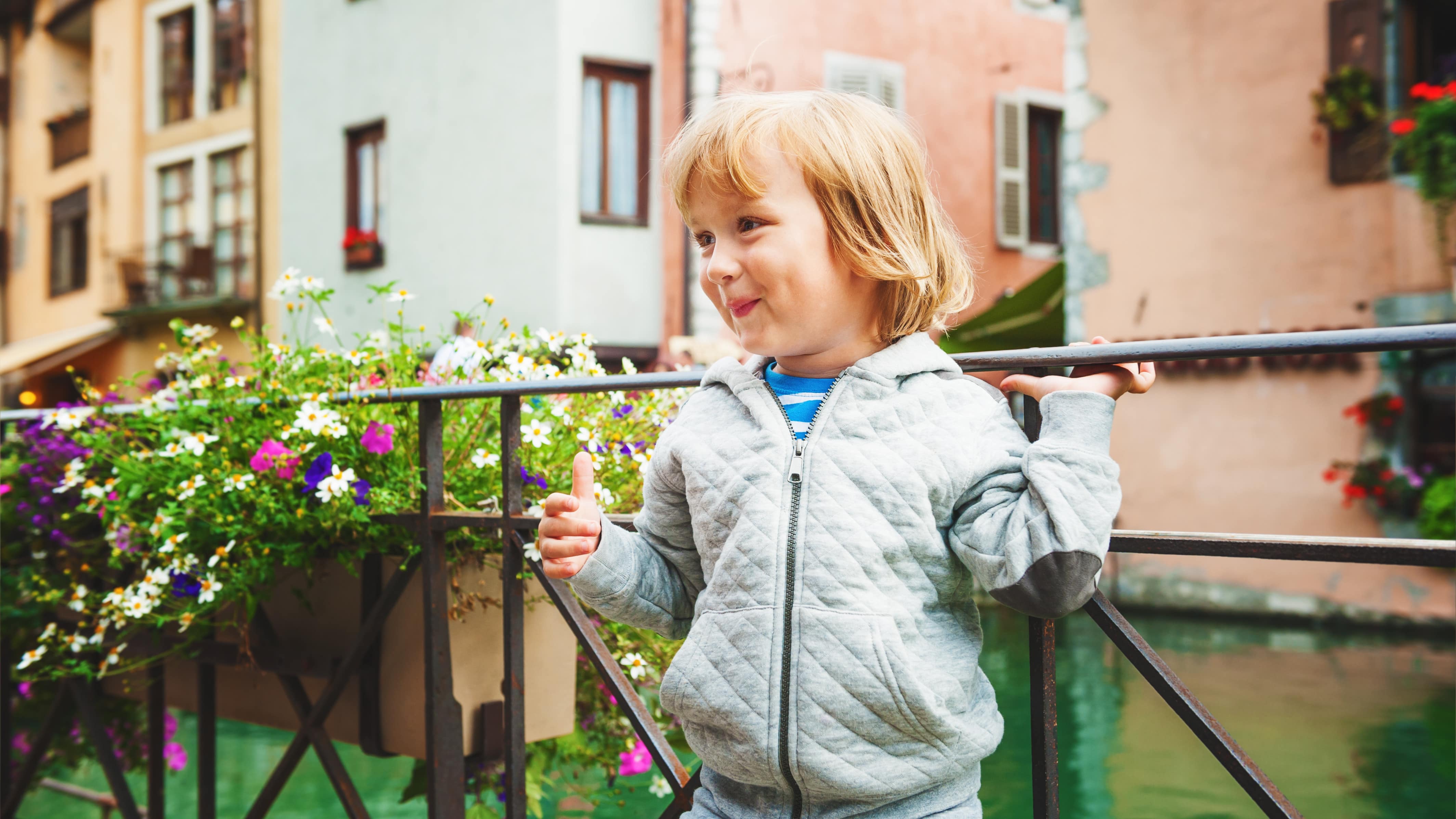 Petite fille adossée au garde-corps d’un pont sur un canal d’Annecy