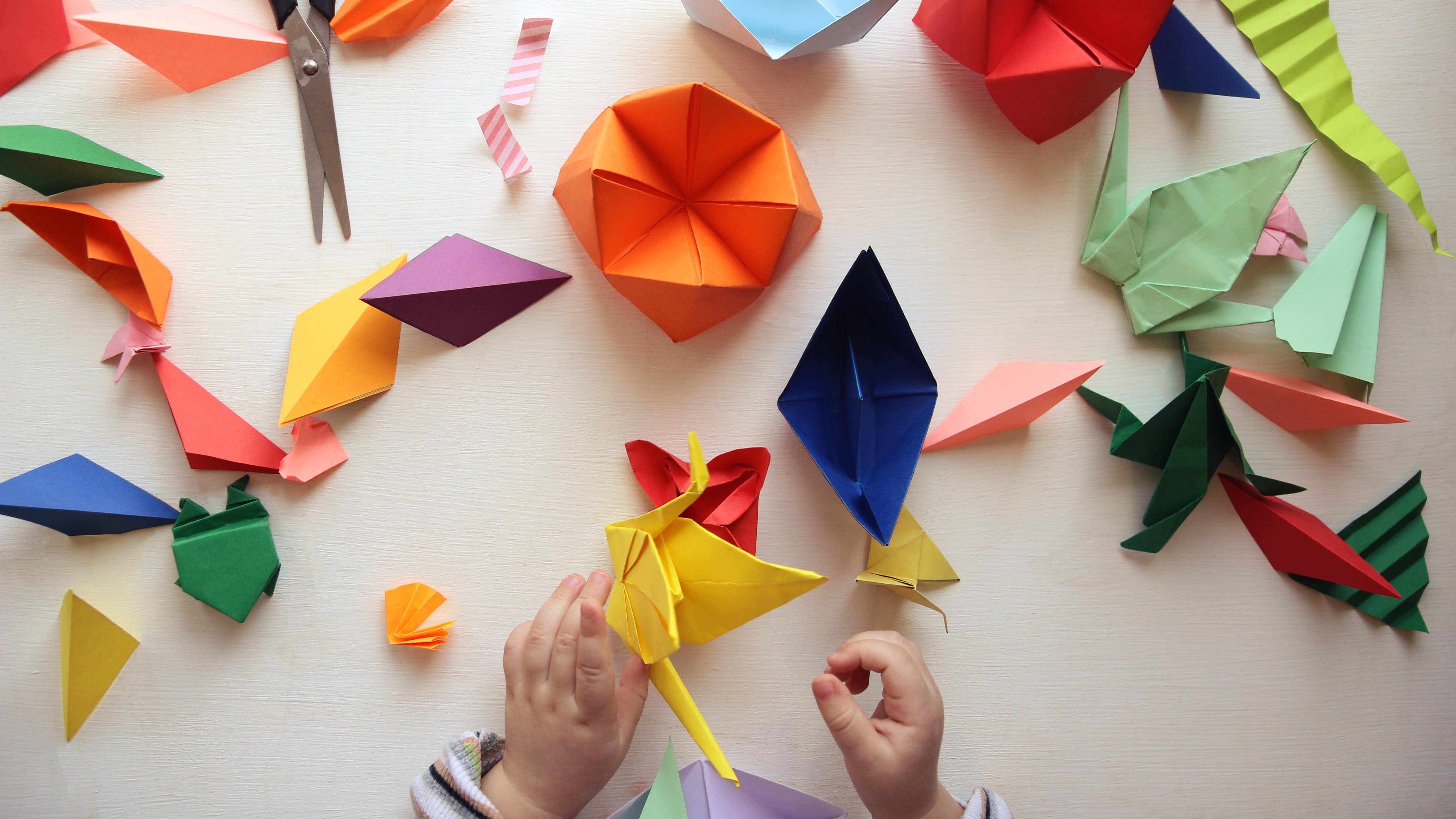 Mains d’enfant devant une table avec plusieurs origamis