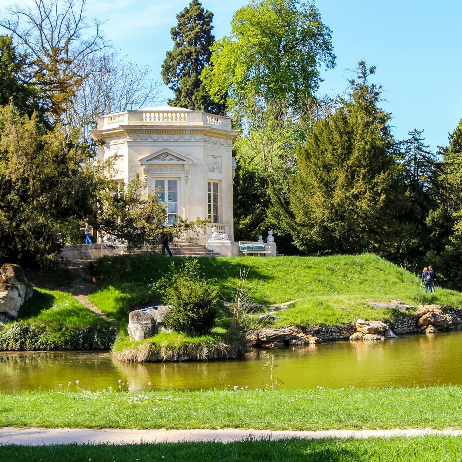 Pavillon isolé dans la verdure. Un plan d'eau verdâtre ceinture une magnifique dépendance dans les jardins de Versailles