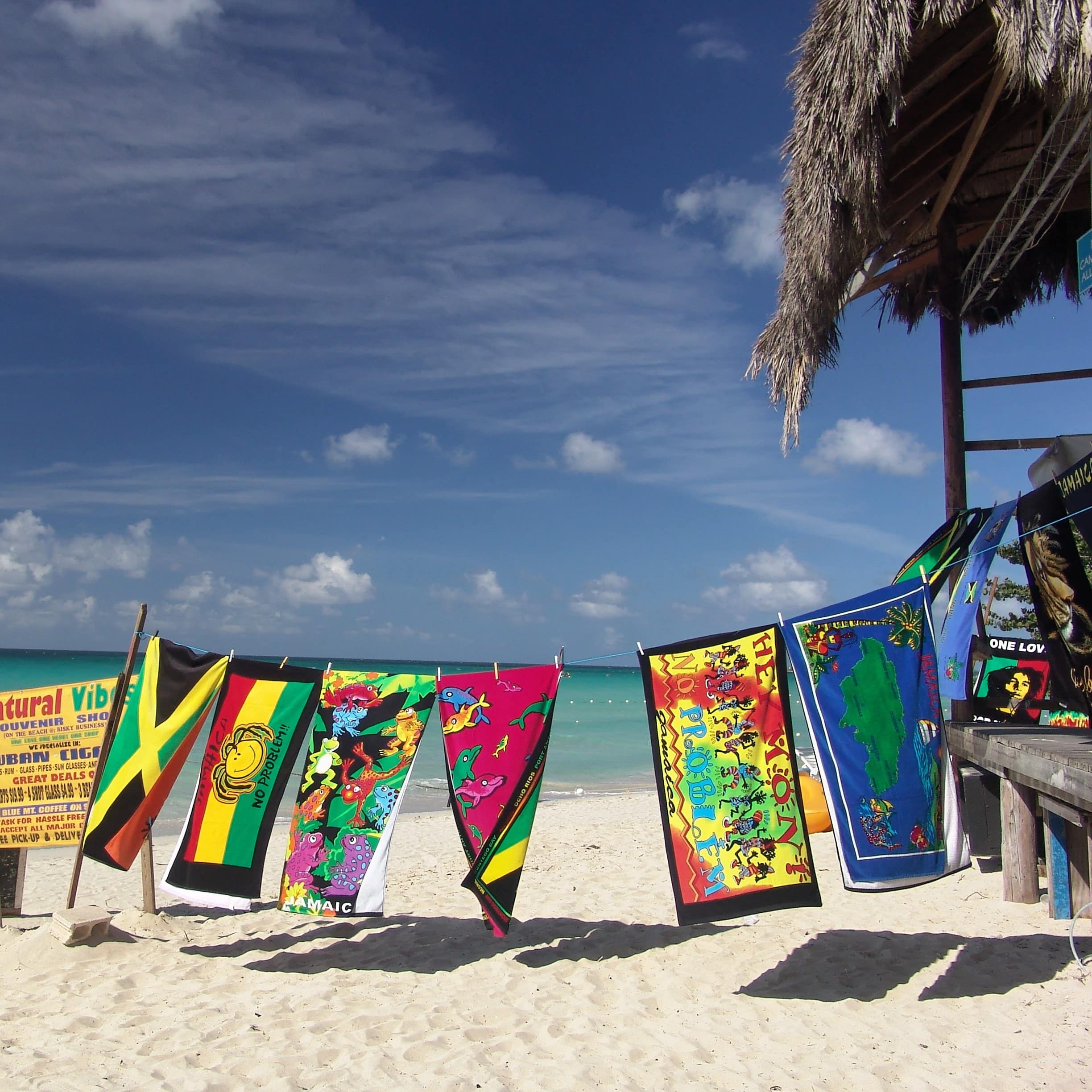 Colorful towels hang on a line above a white-sand beach in Jamaica