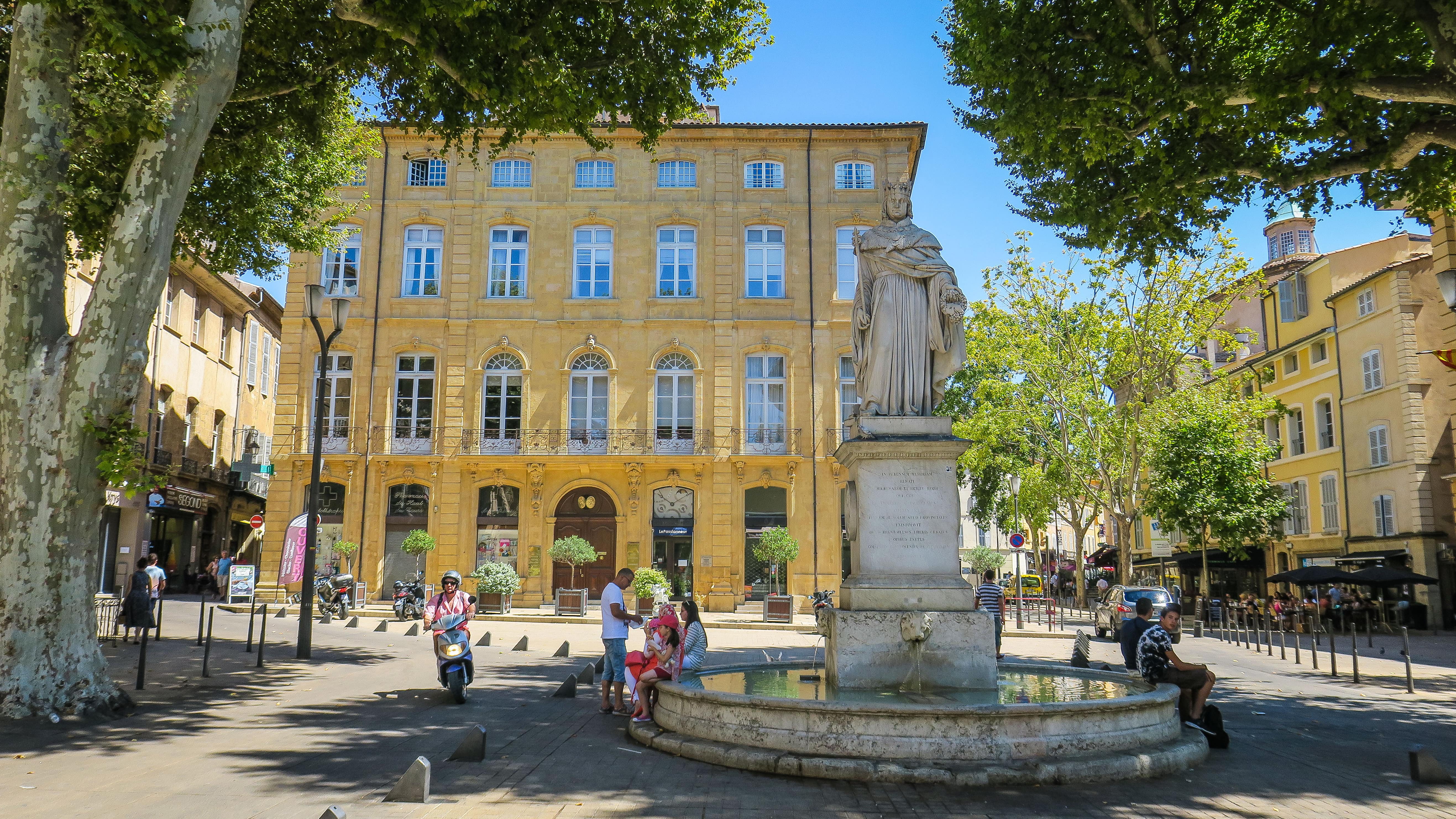 Des personnes assises sur le bord de la fontaine du roi René, cours Mirabeau à Aix-en-Provence