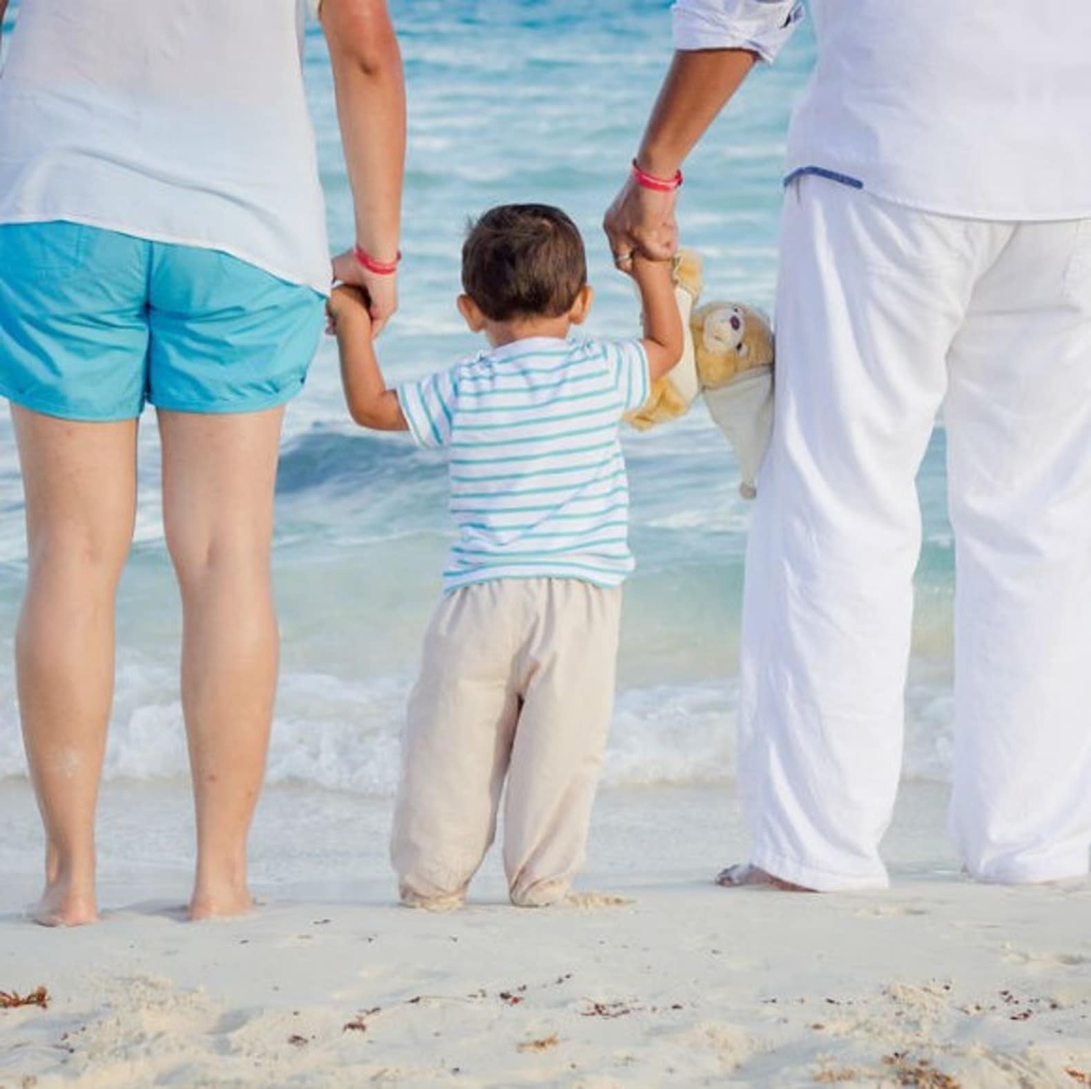 Parents avec leur enfant sur la plage, vacances en famille