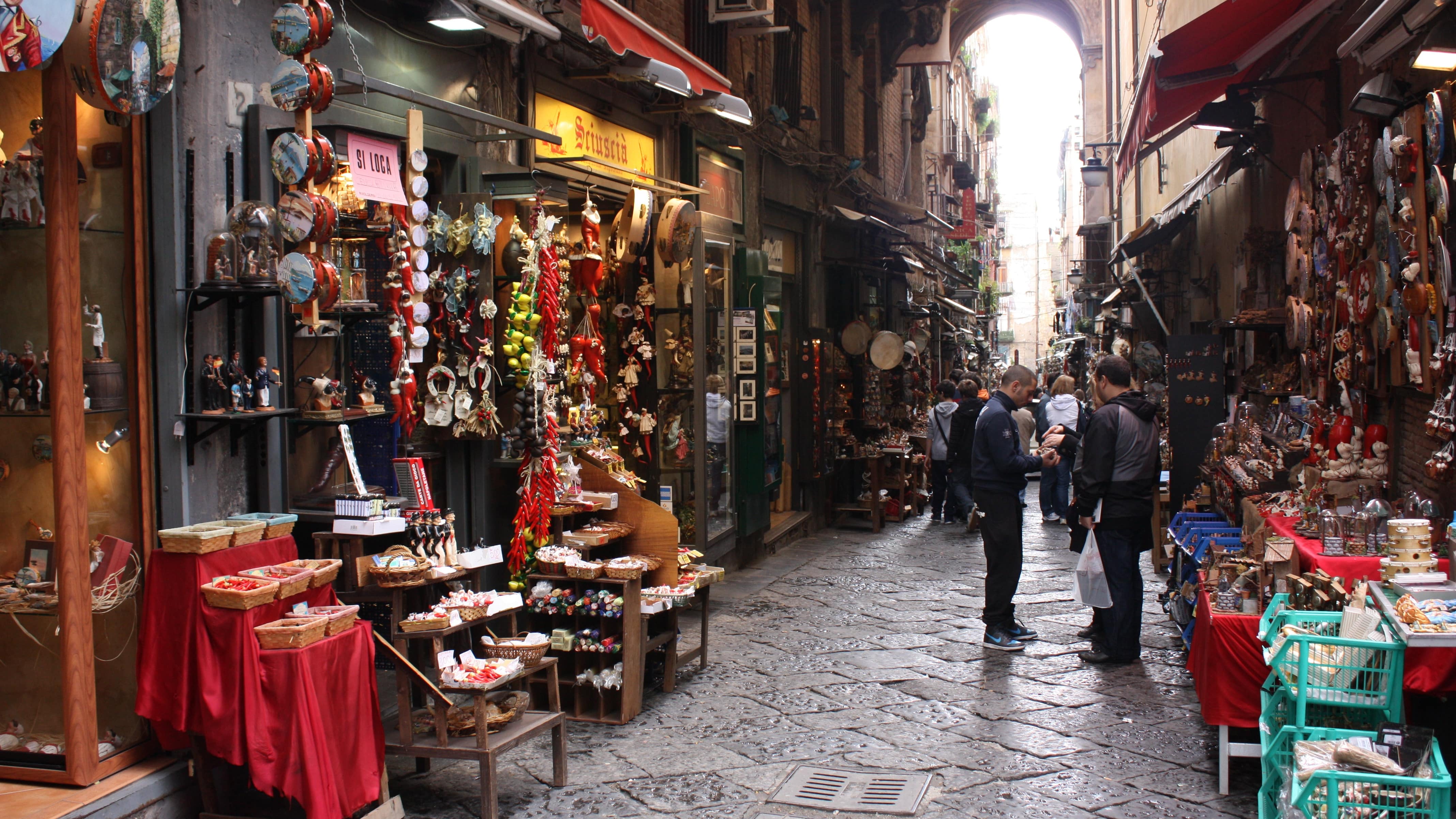 Photo d’une rue piétonne napolitaine bordée de boutiques bien achalandées