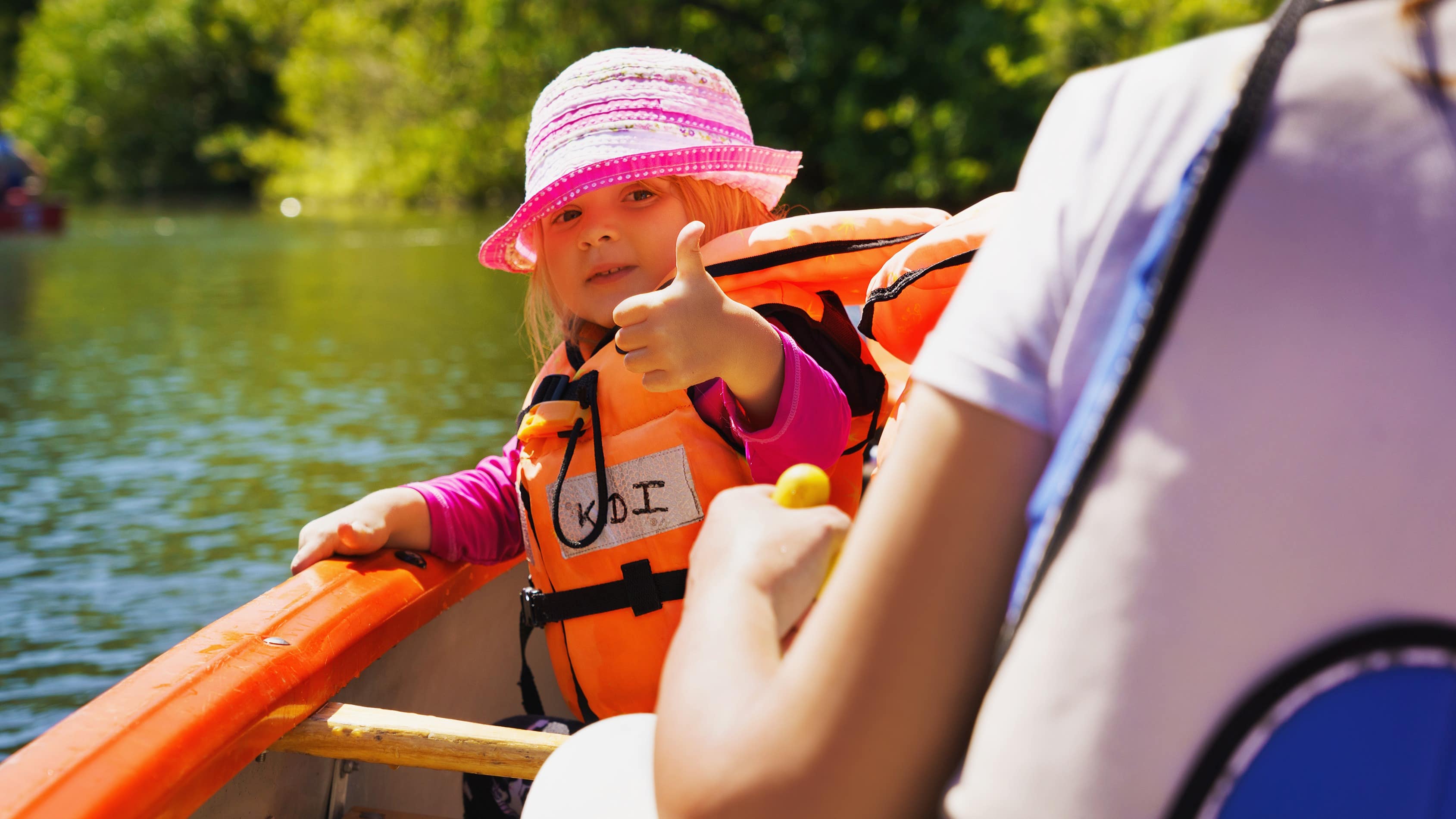 Vue sur un adulte et une enfant dans un kayak, celle-ci se retourne vers l'objectif et affiche un pouce en l'air