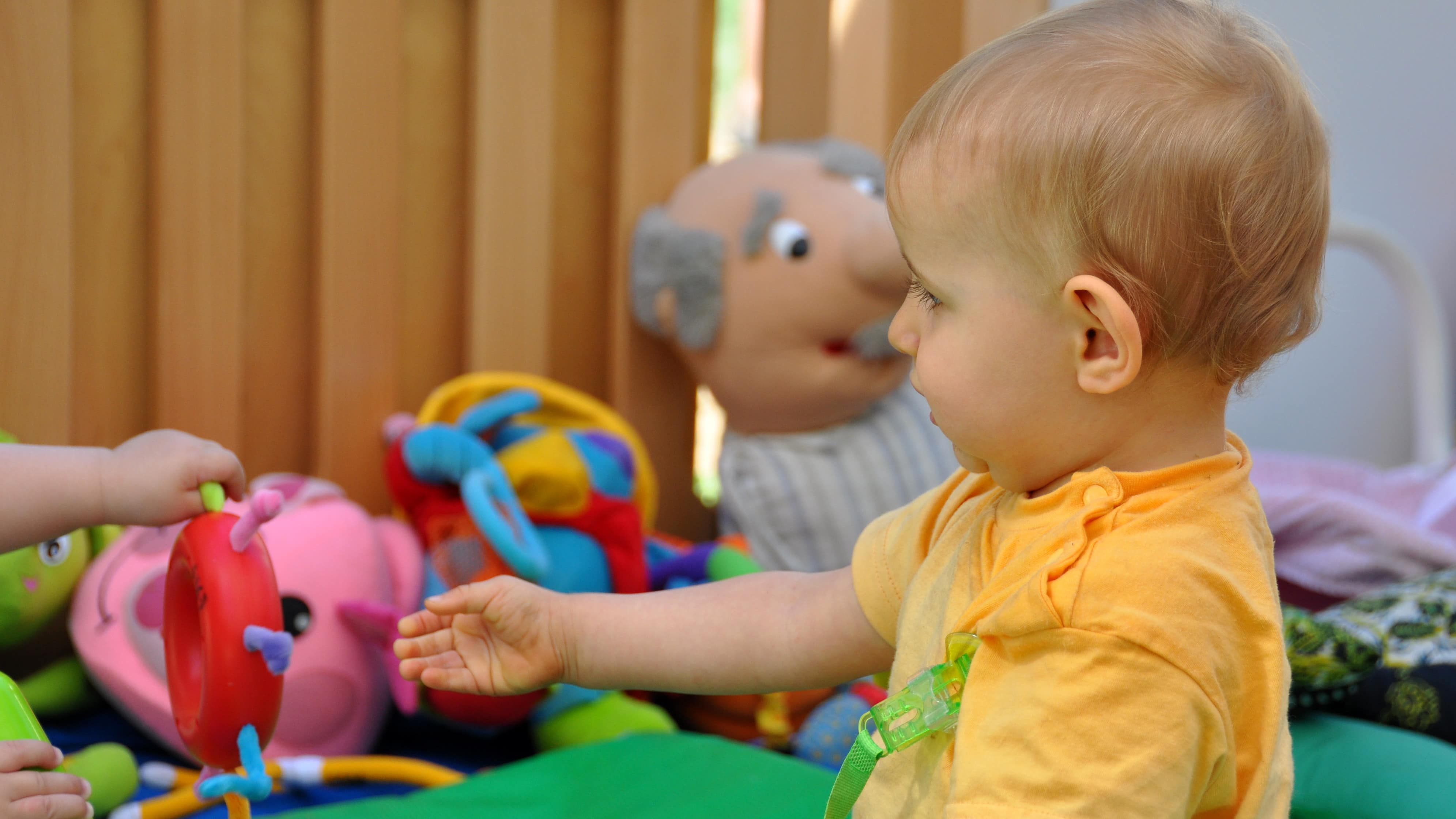 Bébé tendant la main vers un jouet dans l’aire de jeux d’une ludothèque