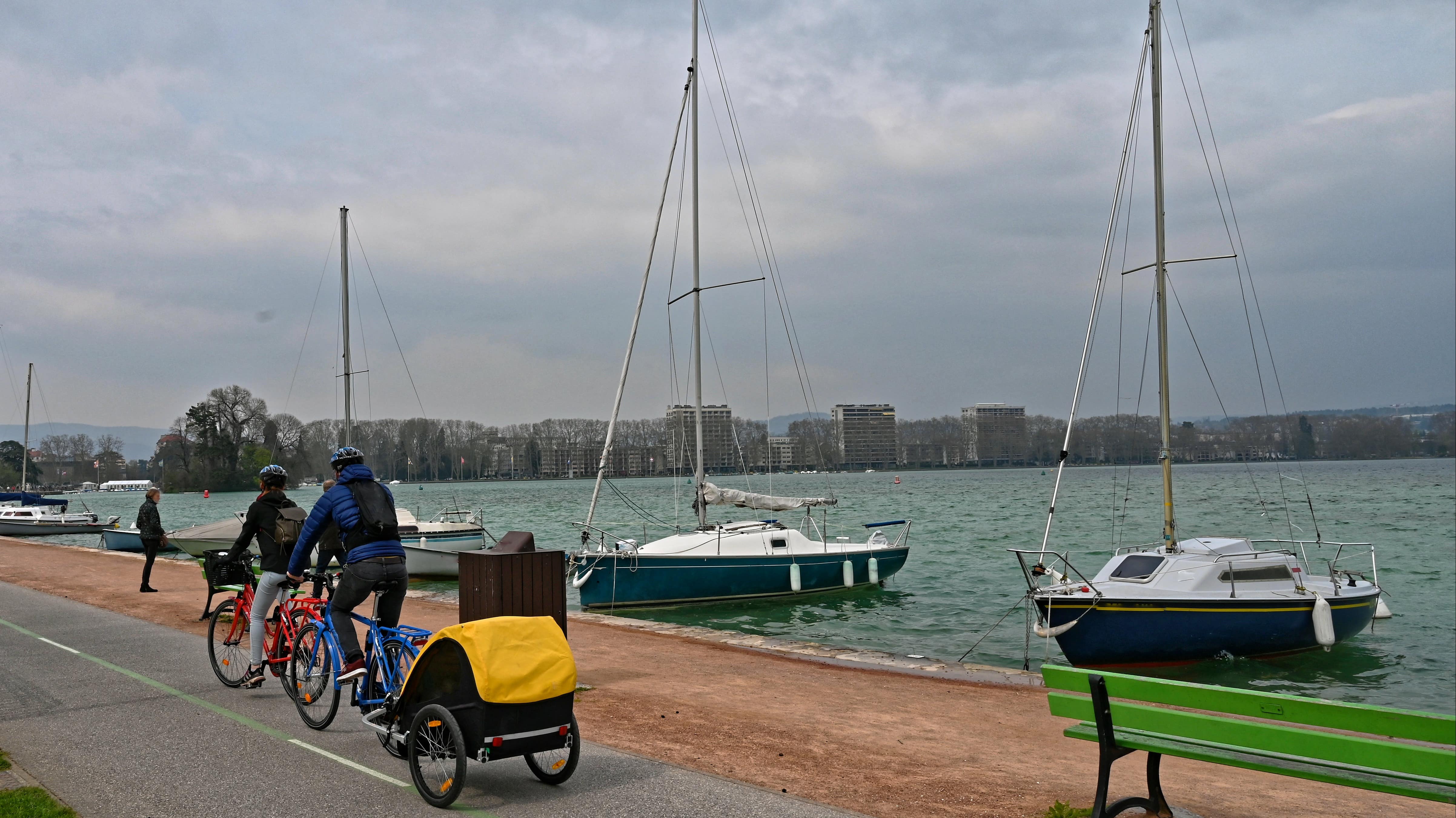 Deux cyclistes, dont l’un tirant une remorque bébé sur les bords du lac d’Annecy