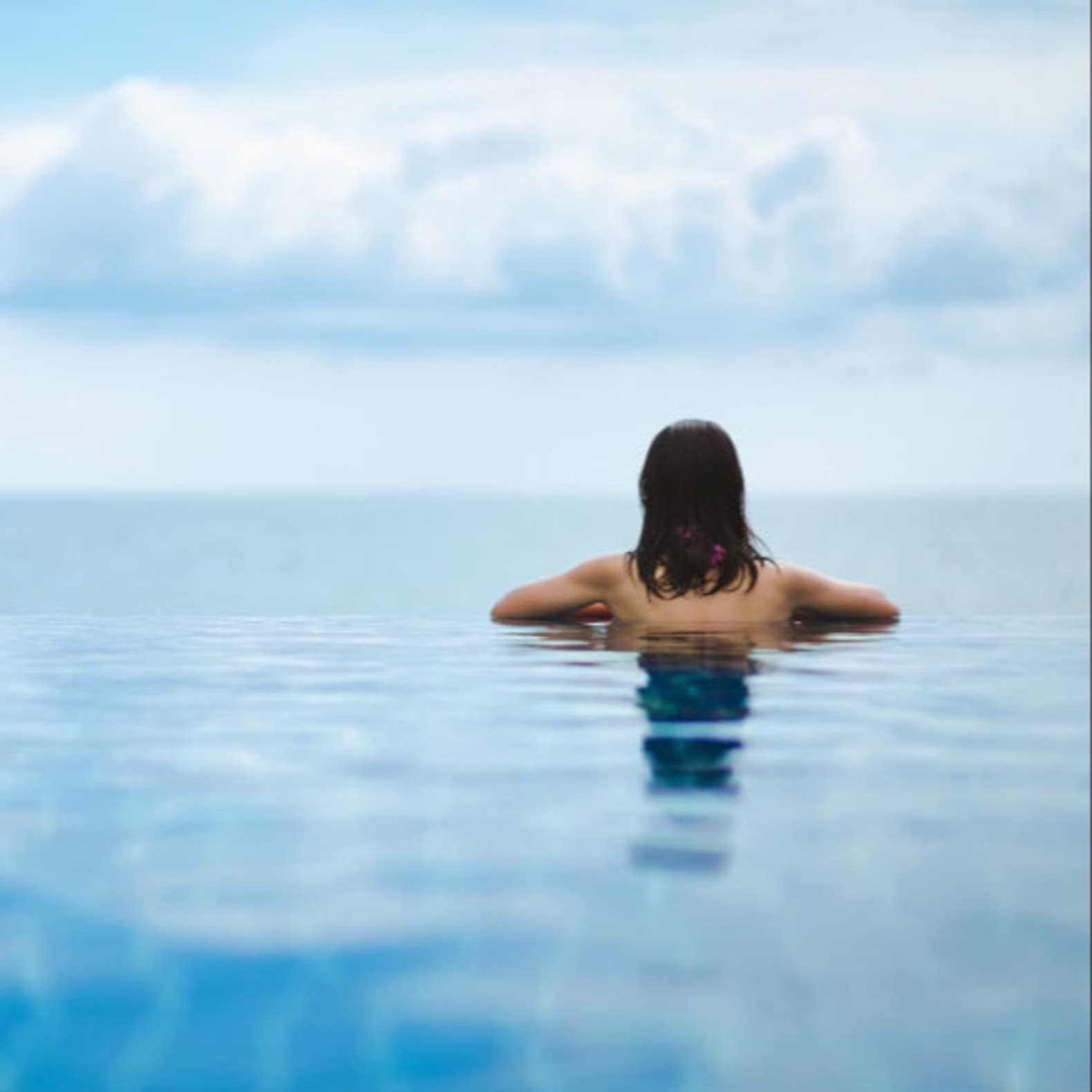 Femme dans une piscine à débordement avec vue sur la mer, location maison avec piscine