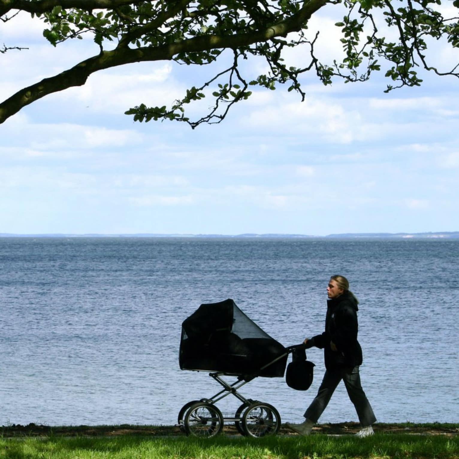 Femme avec une poussette au bord de l’eau, vacances avec bébé