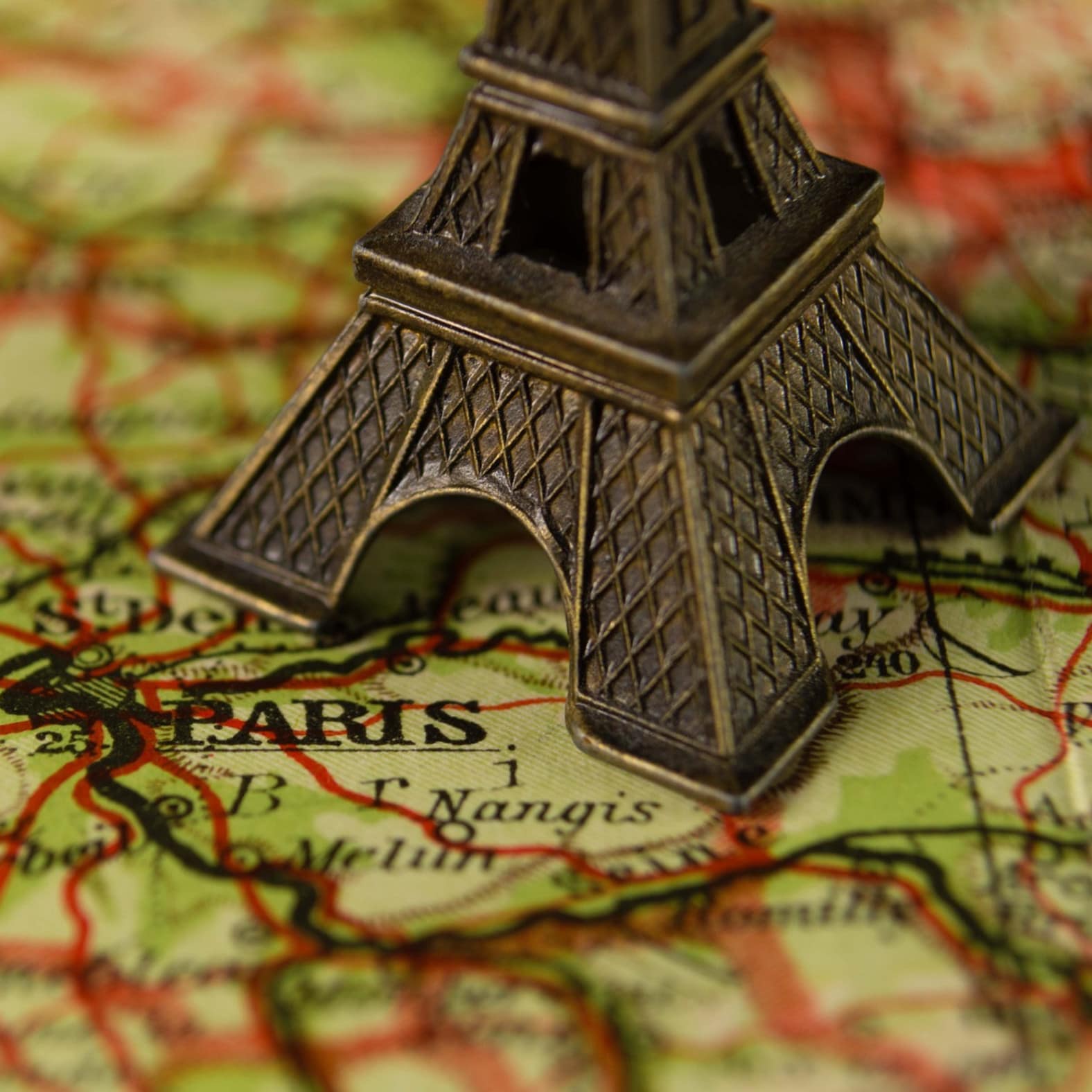 Gros plan sur une carte de France, où le mot PARIS est imprimé au pied d'une tour Eiffel en métal cuivré