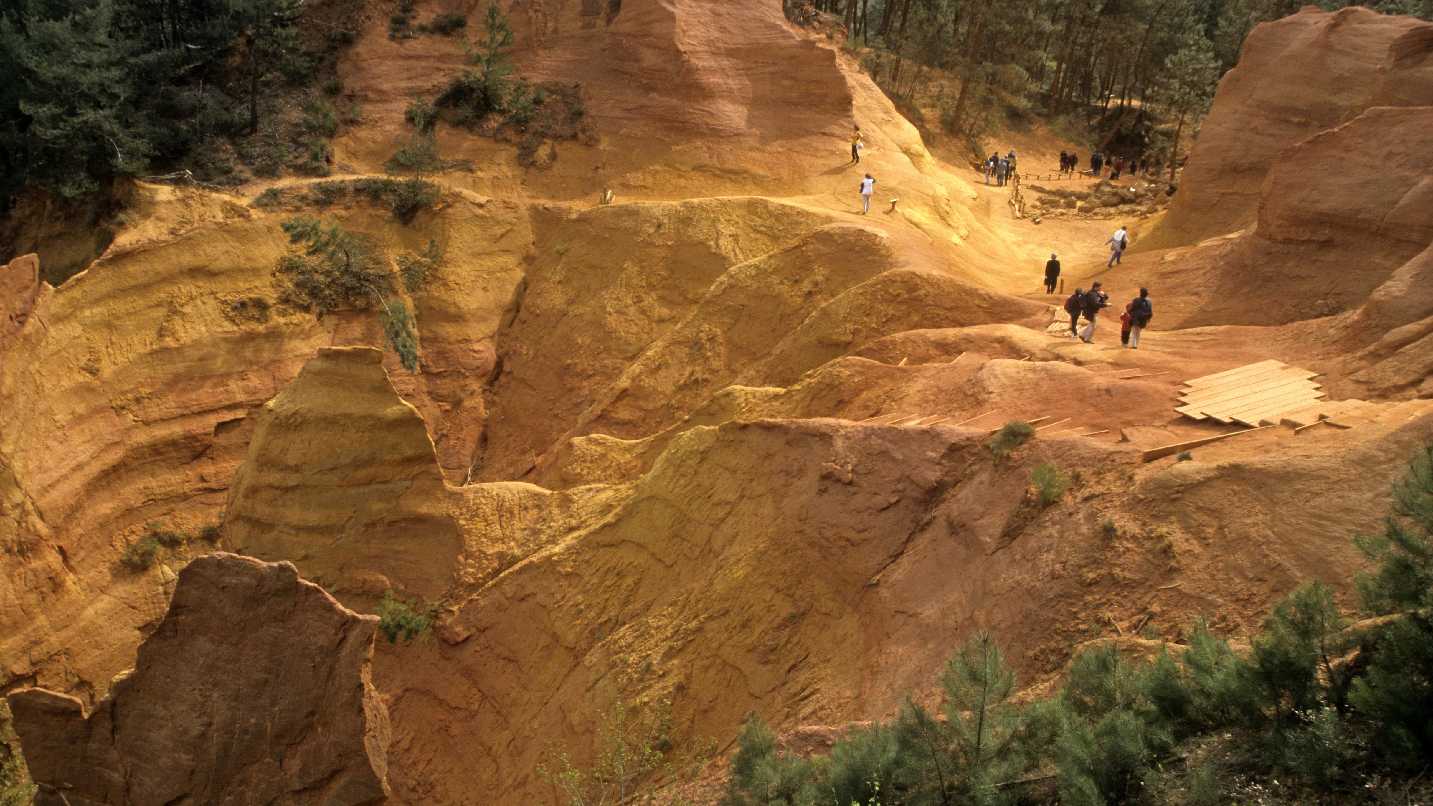 Quelques personnes qui se promènent au milieu des falaises ocres de Roussillon, dans le Parc naturel régional du Luberon
