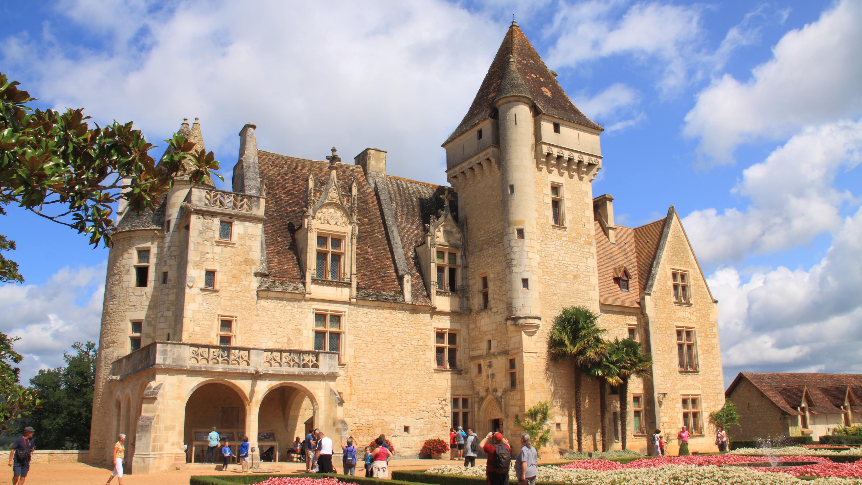 Des visiteurs dans les jardins fleuris devant le château des Milandes