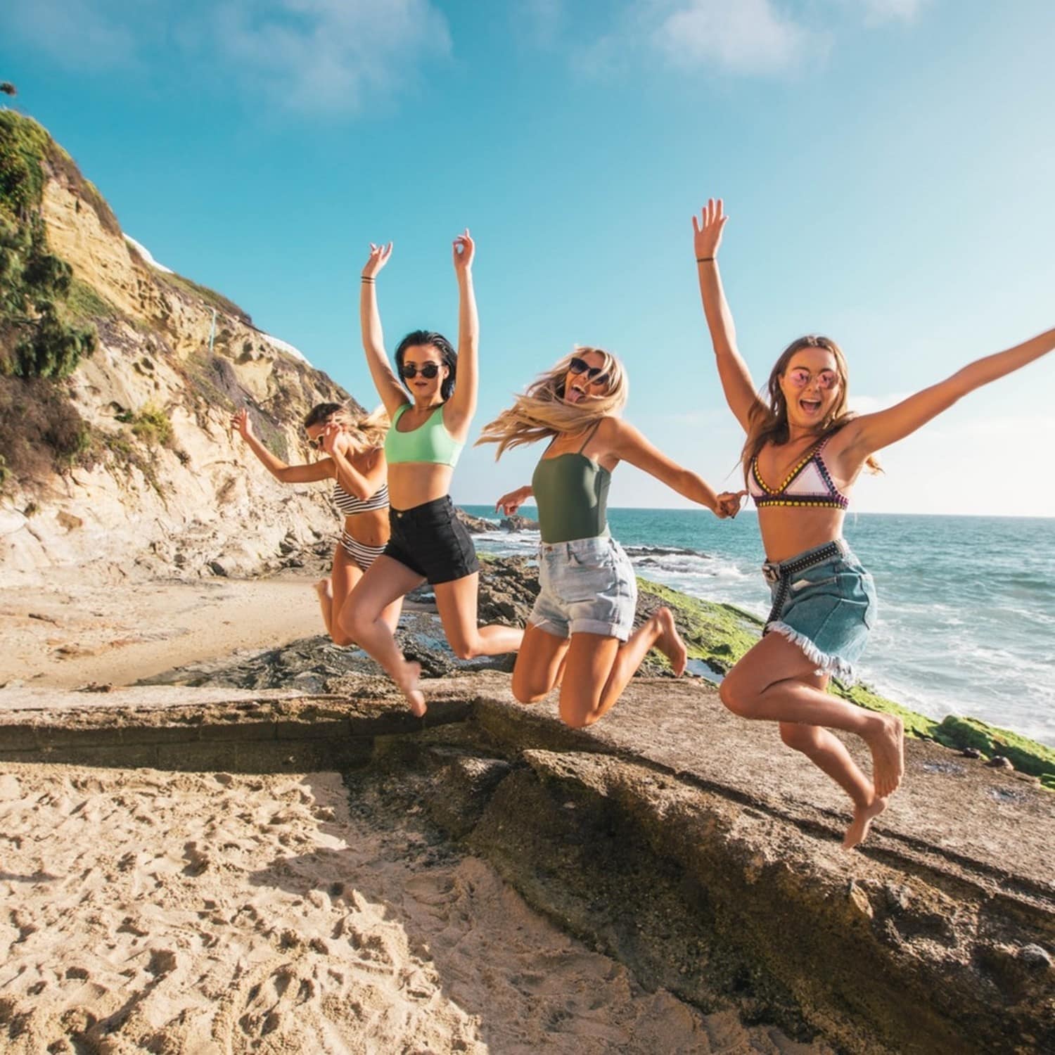 Groupe de quatre femmes s'amusant sur la plage près de la mer