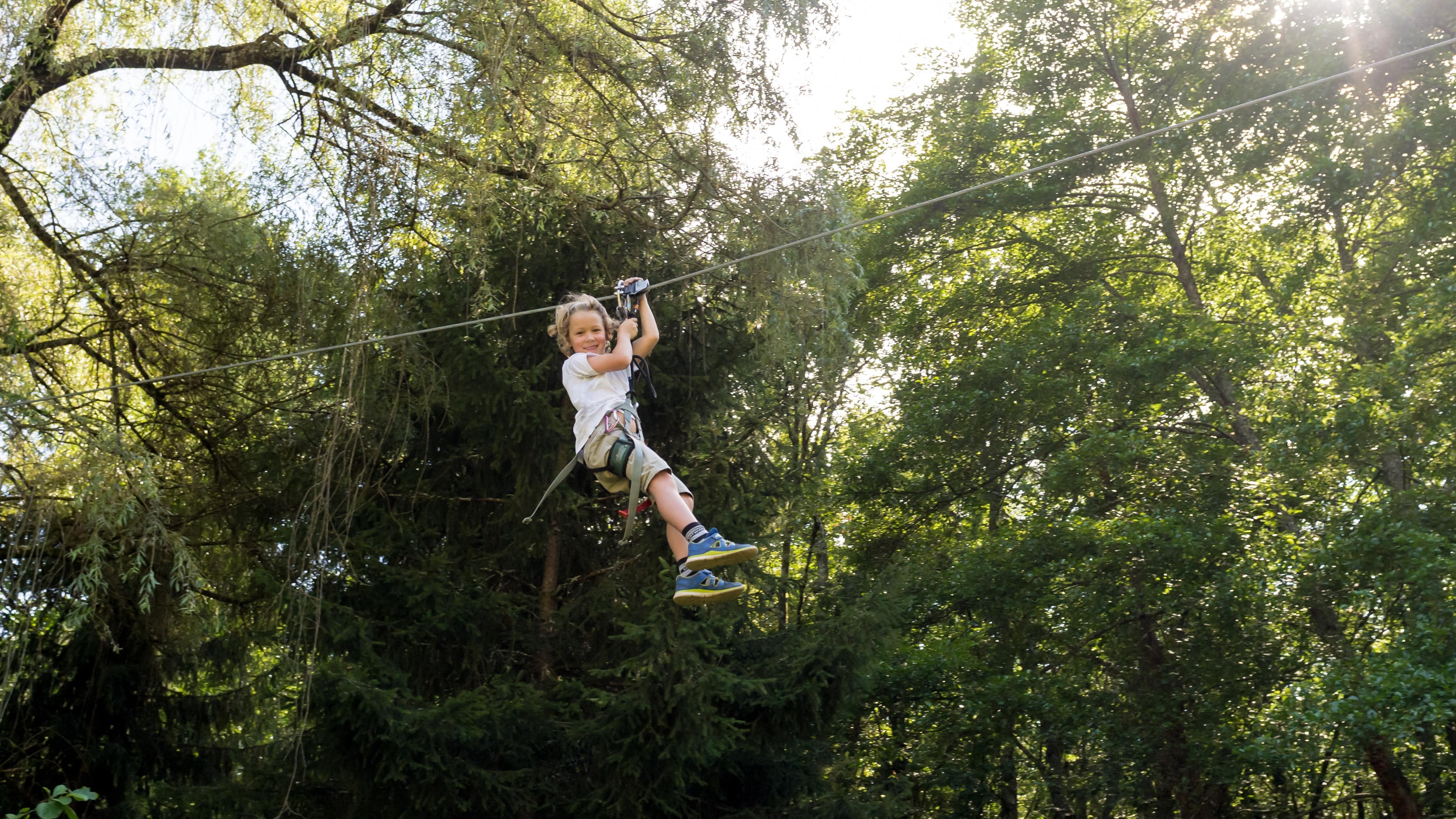 Enfant sur une tyrolienne au milieu des arbres