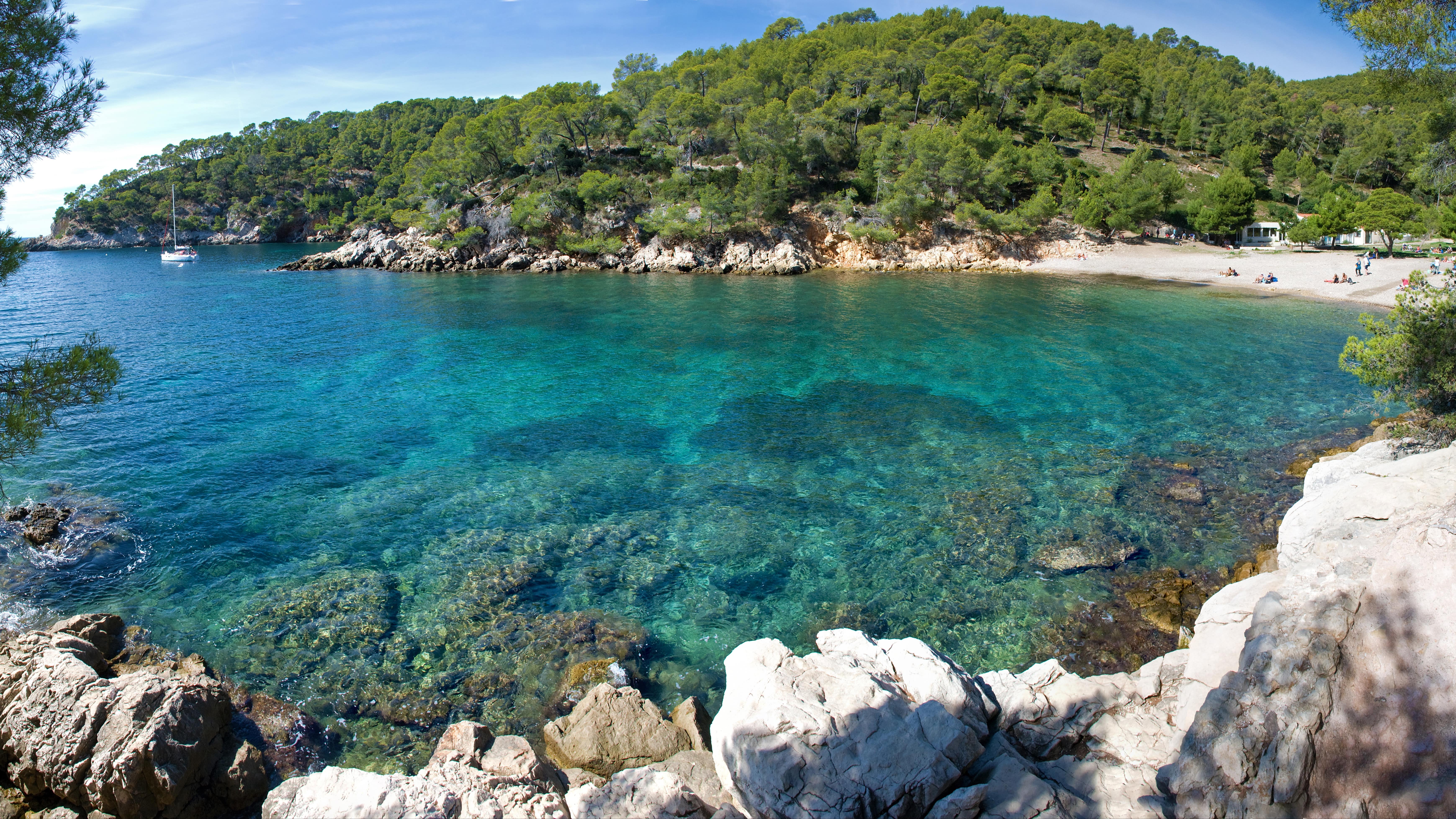 Rochers, plage et colline verdoyante au bord de l’eau, à la calanque du Port d’Alon dans le Var