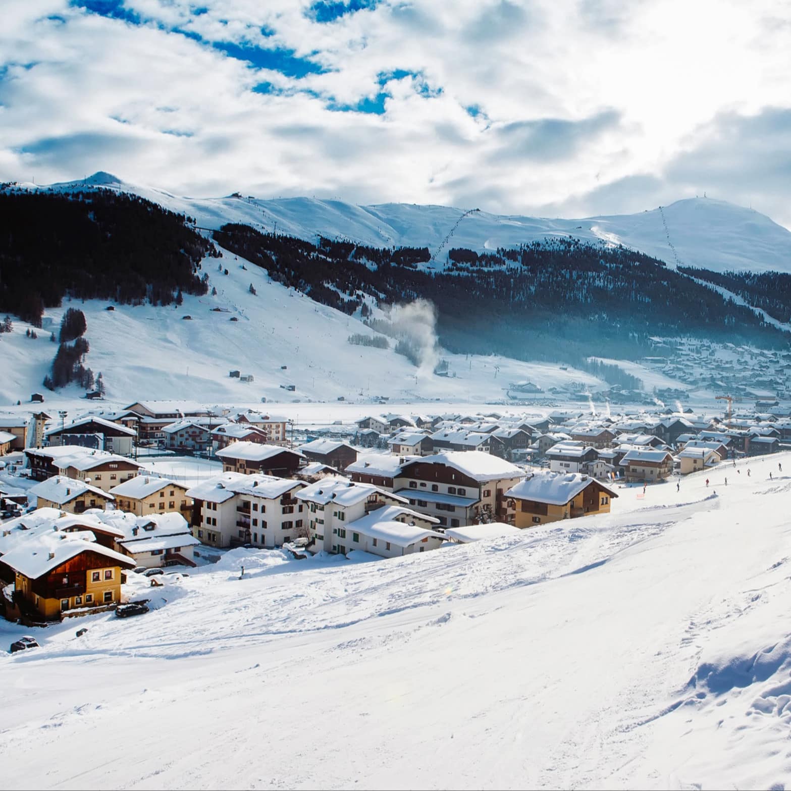 Une station de ski en montagne composée de plusieurs chalets enneigés en pleine journée