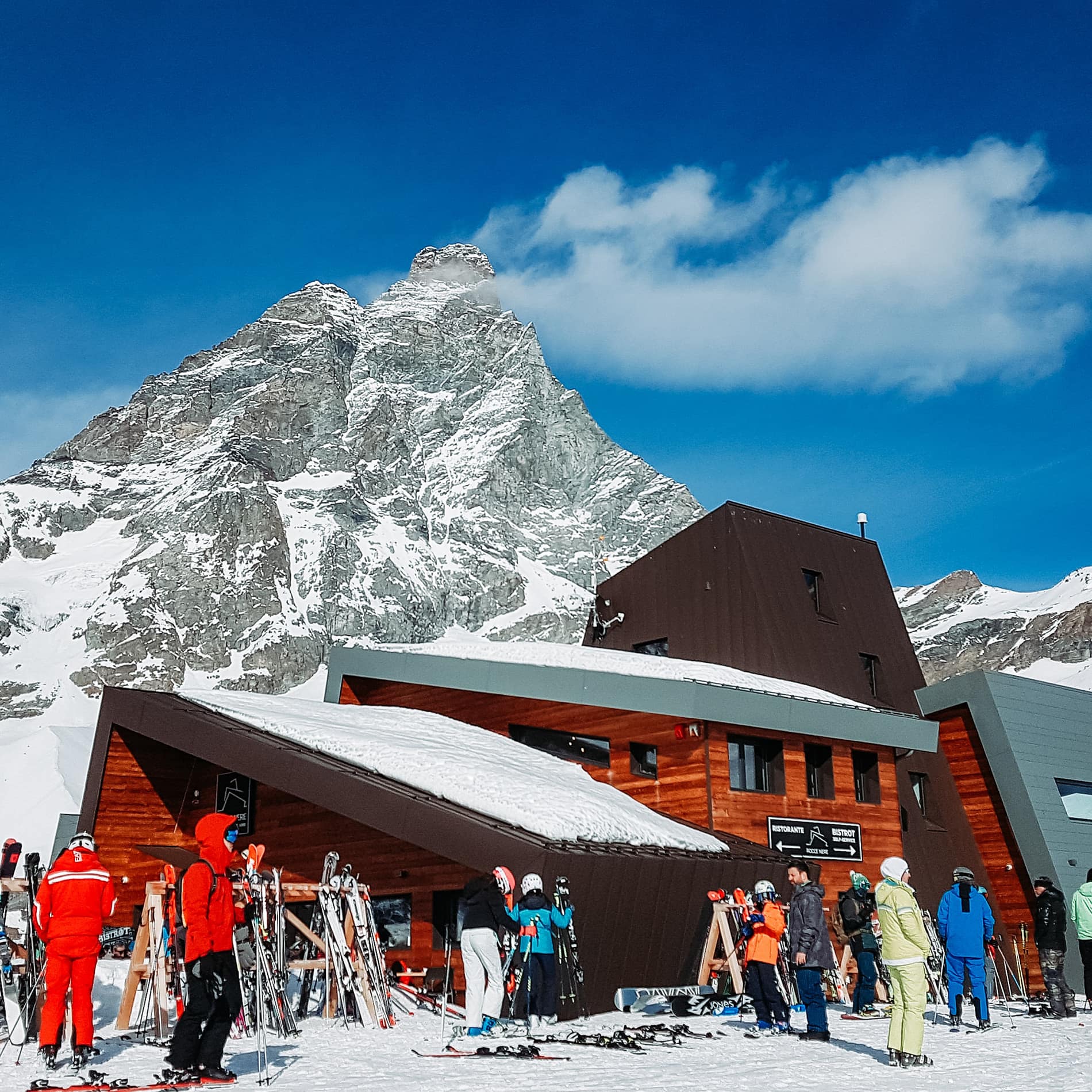 People standing on snow near wooden house