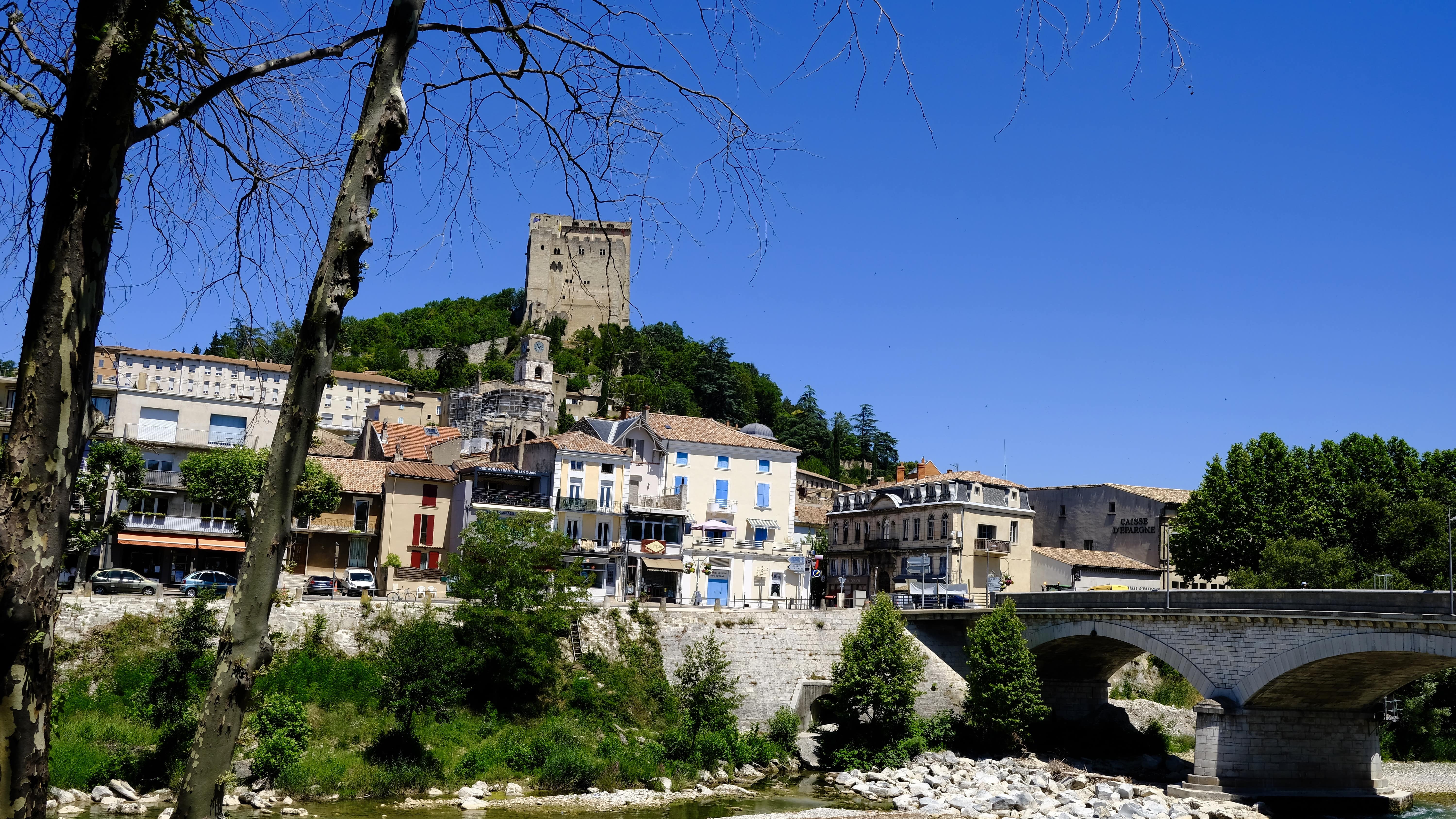 Vue depuis les rives de la Drôme sur le village de Crest avec sa haute tour perchée en haut de la colline