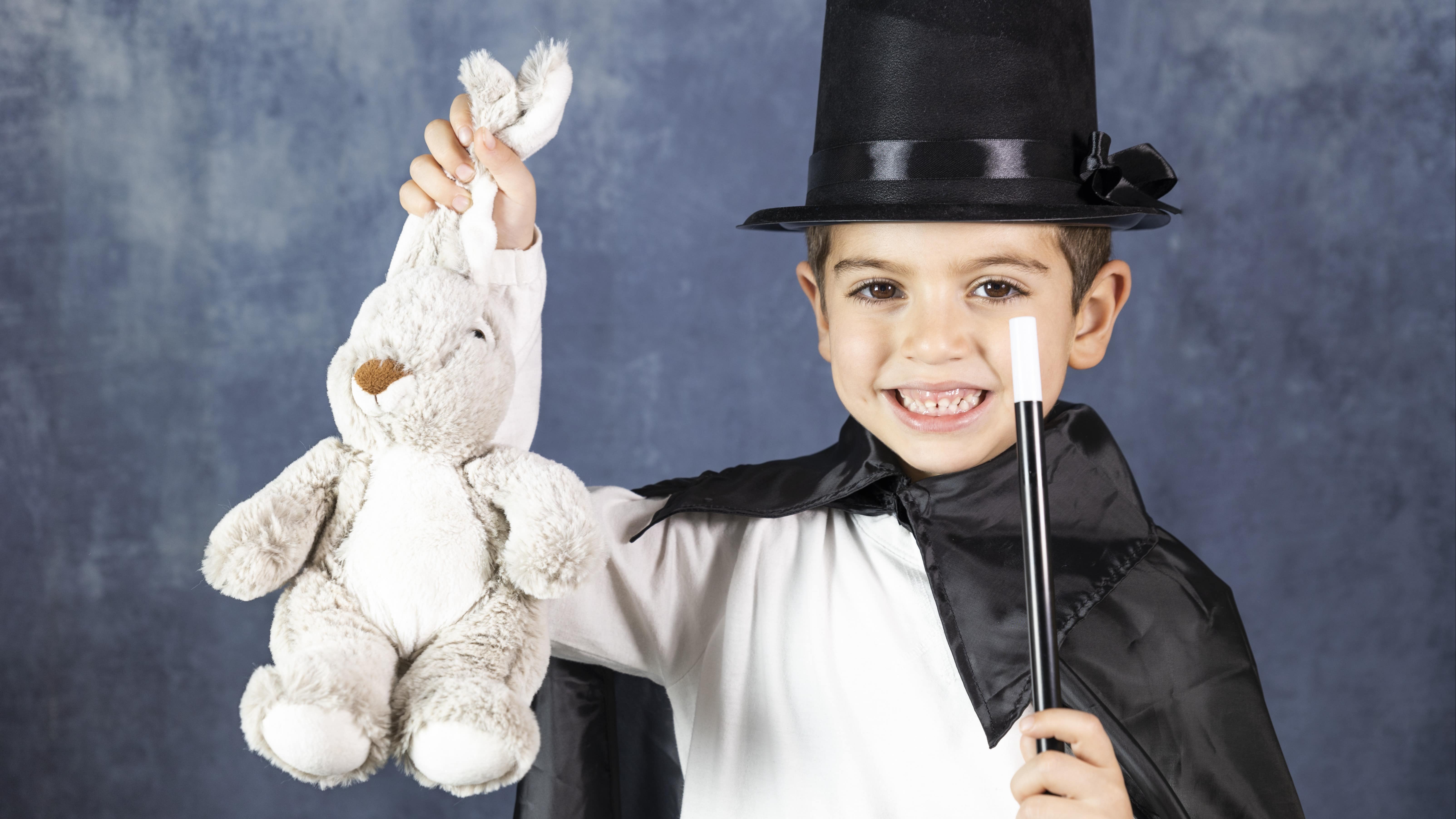 Enfant faisant un tour de magie avec un lapin en peluche qu’il sort d’un chapeau