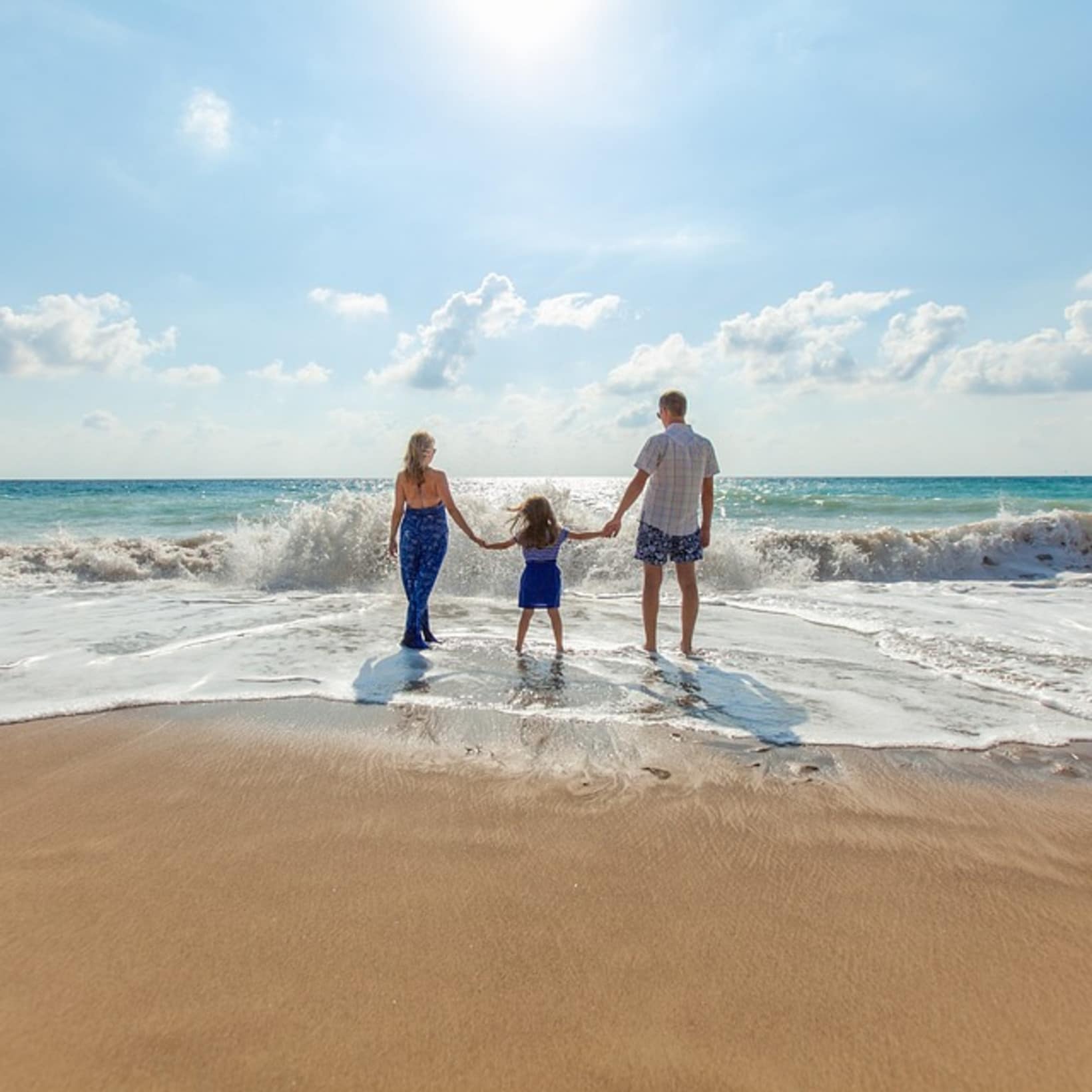 Couple avec un enfant sur la plage, vagues, vacances pas cher en famille en aout